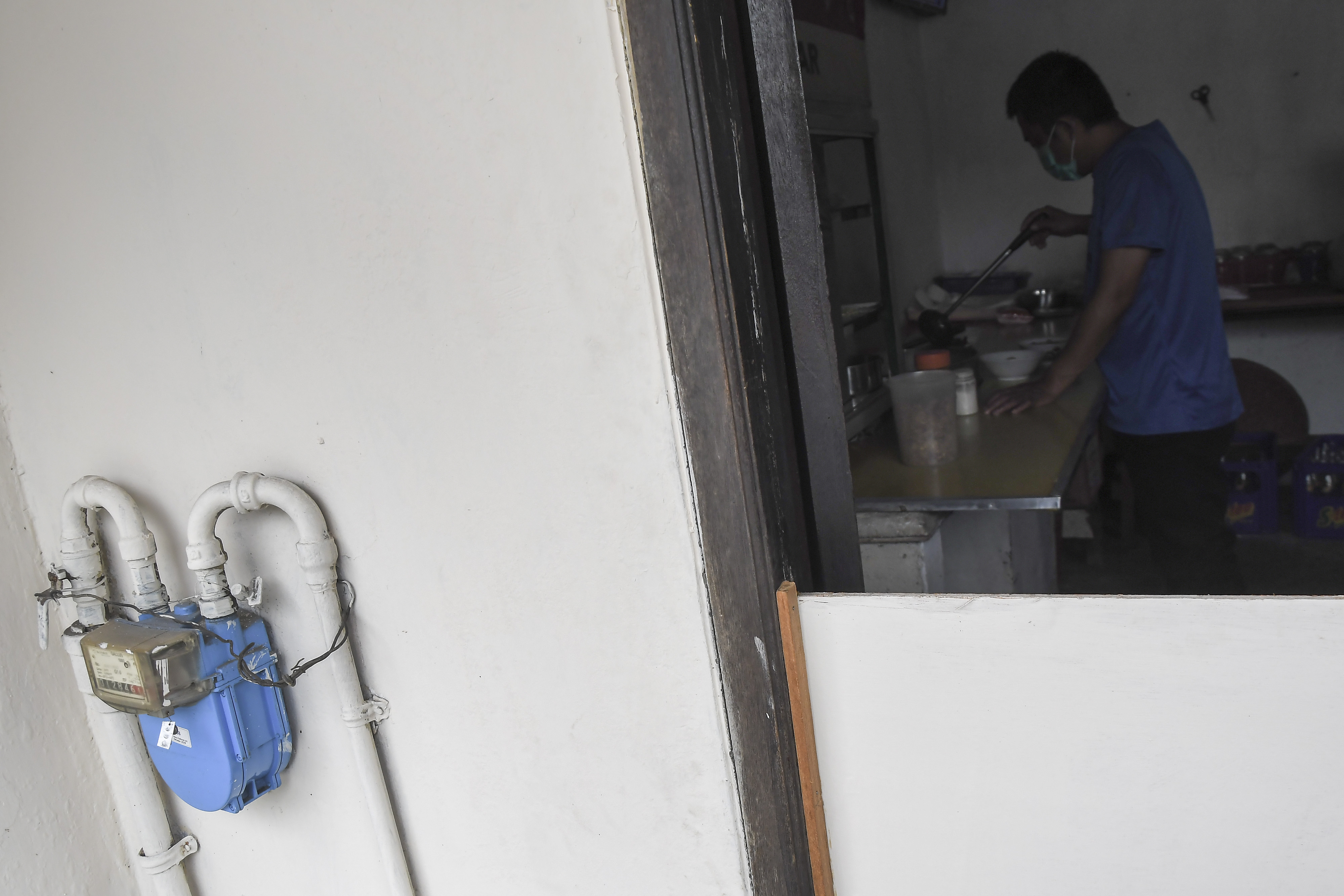 Pedagang melakukan pengemasan makanan yang dimasak dengan menggunakan bahan bakar gas bumi.