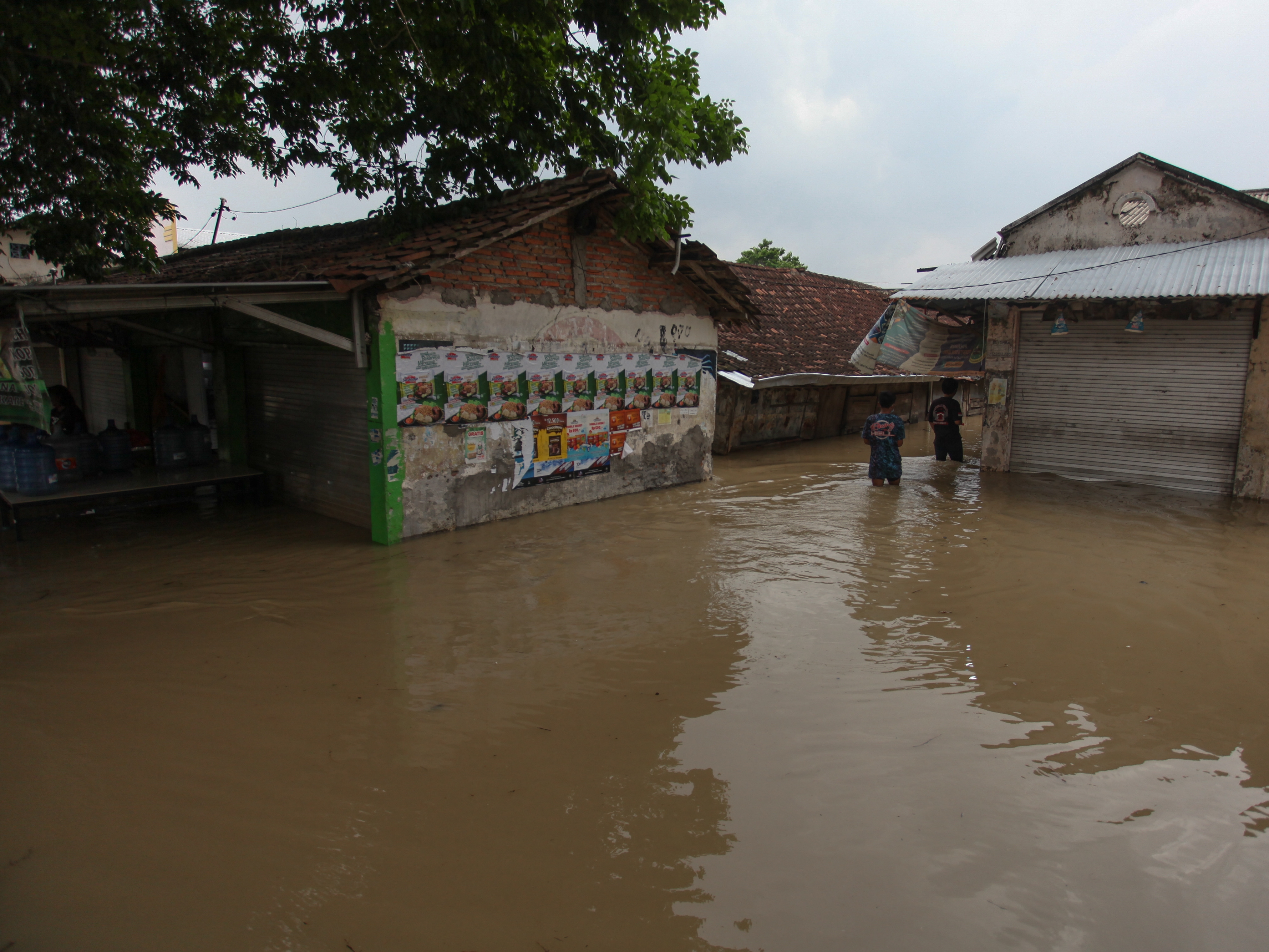 Warga berusaha menerobos banjir akibat air Kali Lamong meluap di Pasar Benjeng, Gresik, Jawa Timur, Jumat (5/11/2021).