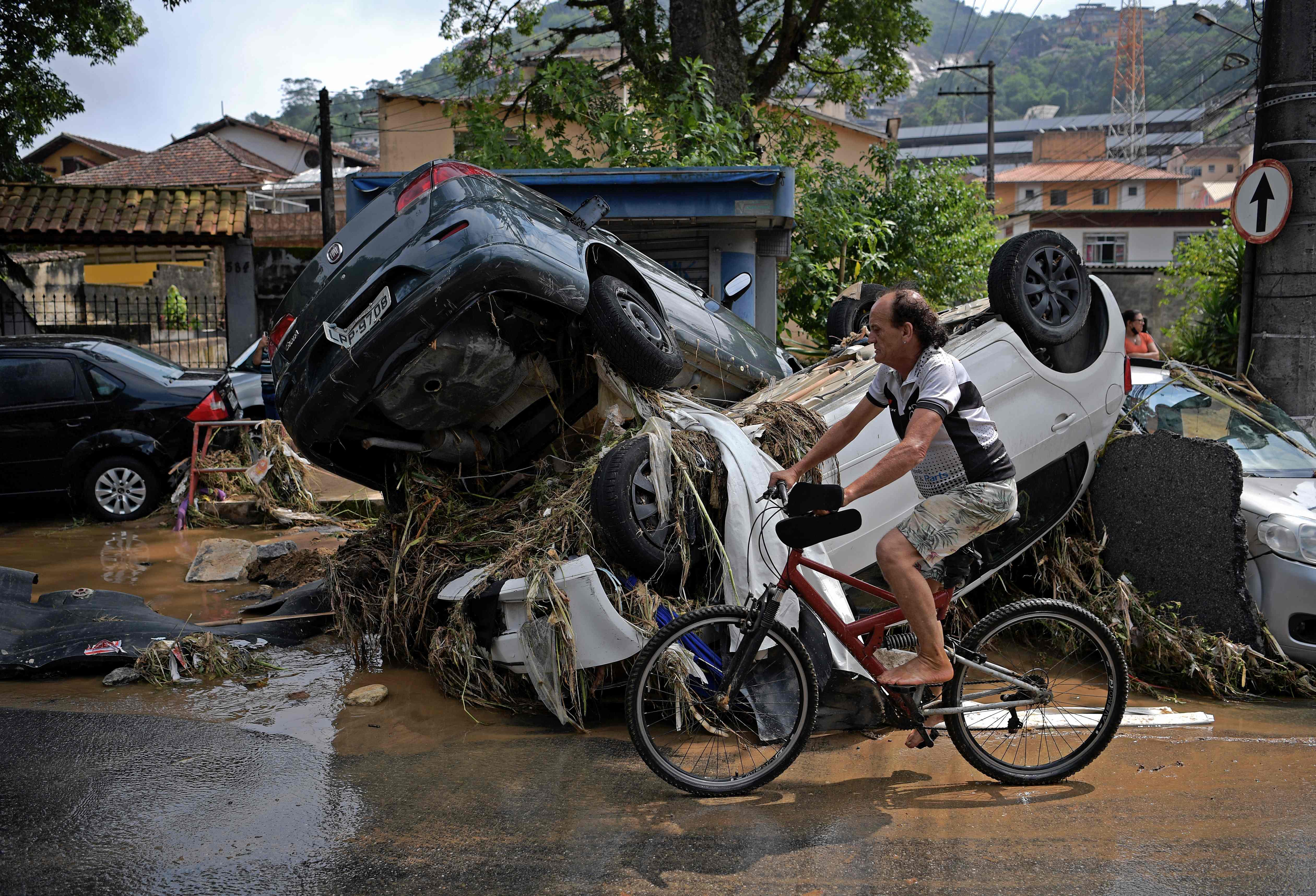 Warga melintas tumpukan mobil yang terjadi akibat banjir di Kota Petropilis, Brasil.