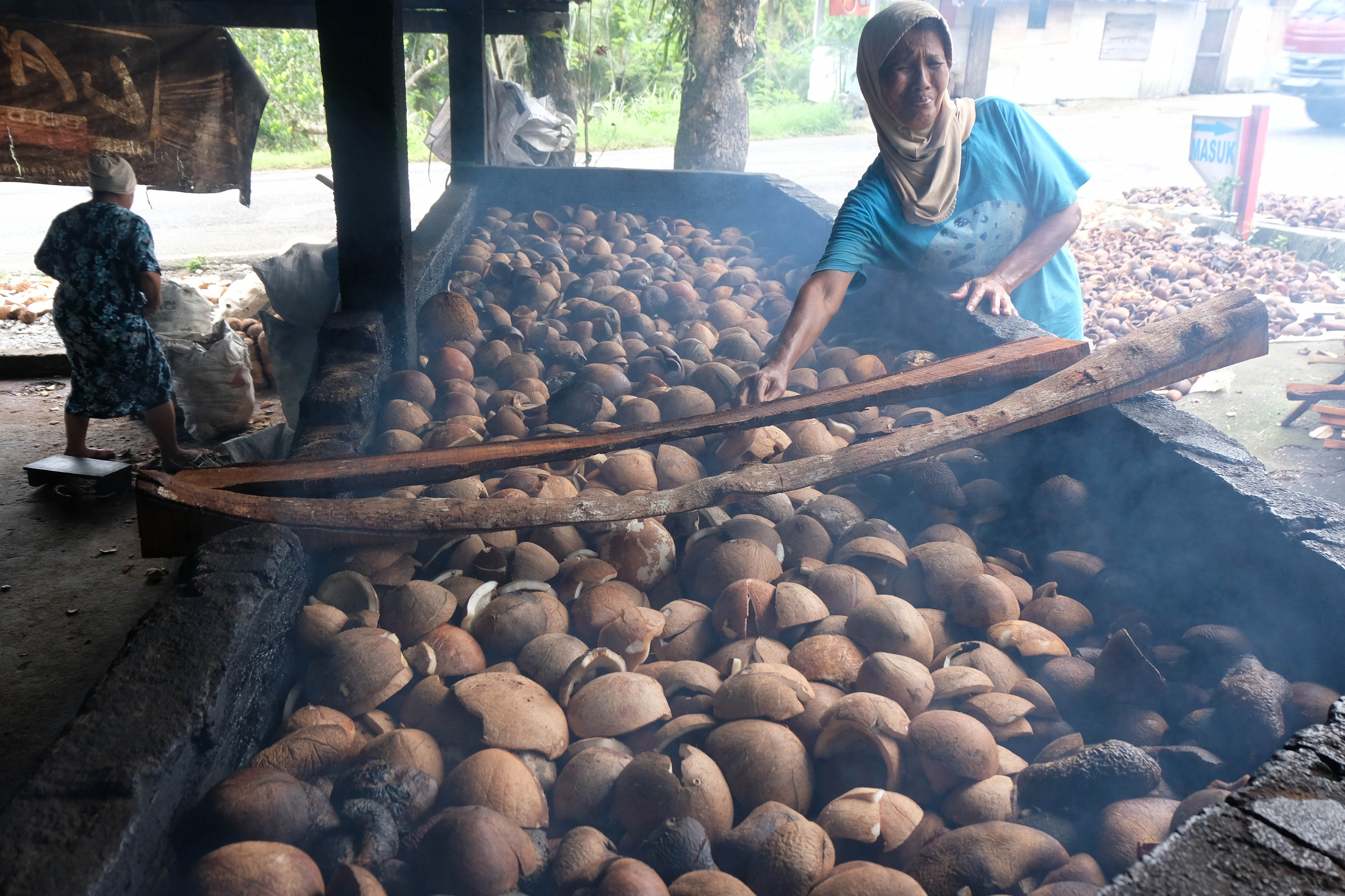 Warga memanggang daging kelapa untuk memperoleh minyak kelapa atau kopra