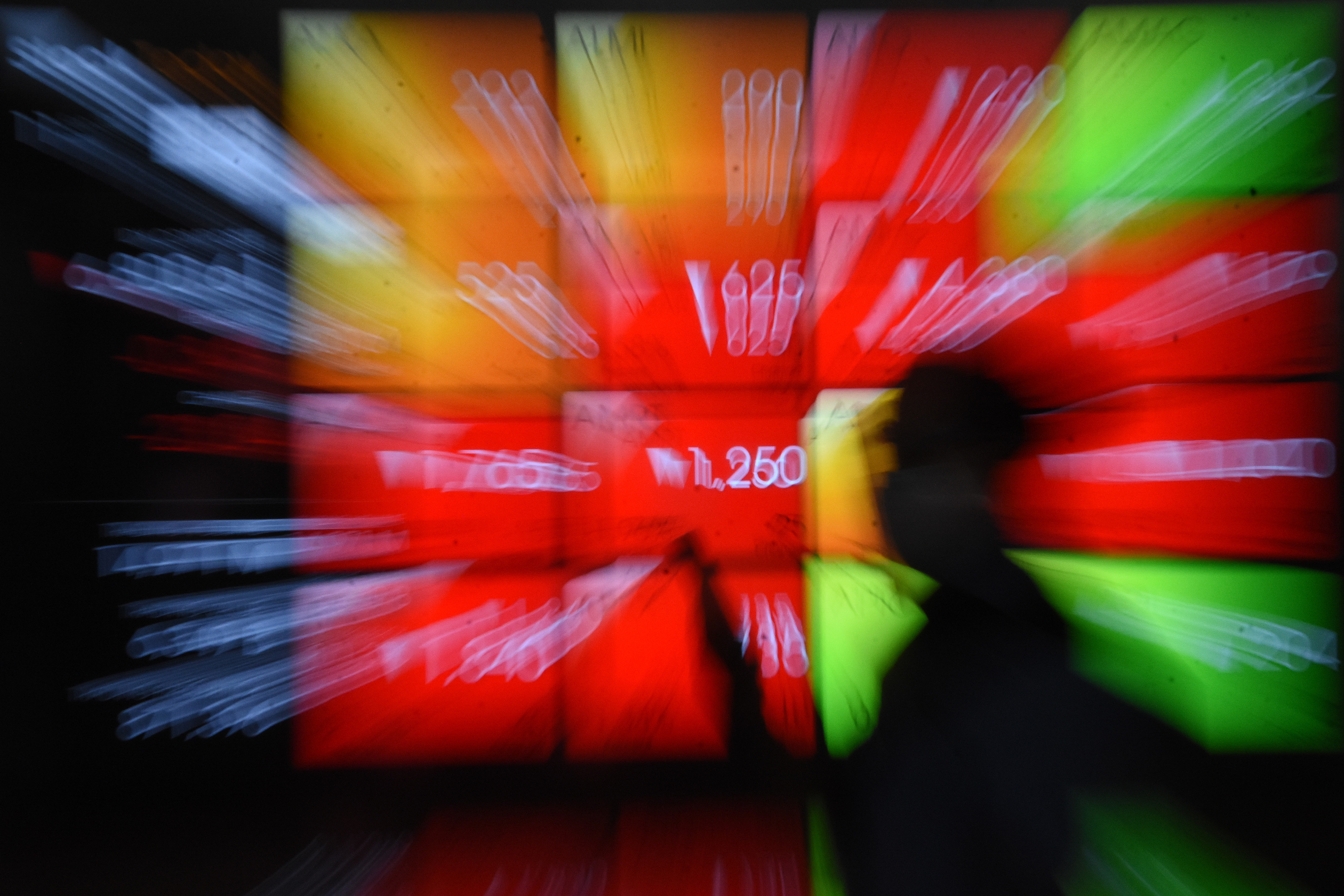 Pekerja melintas di depan layar indeks harga saham di Bursa Efek Indonesia, Jakarta.