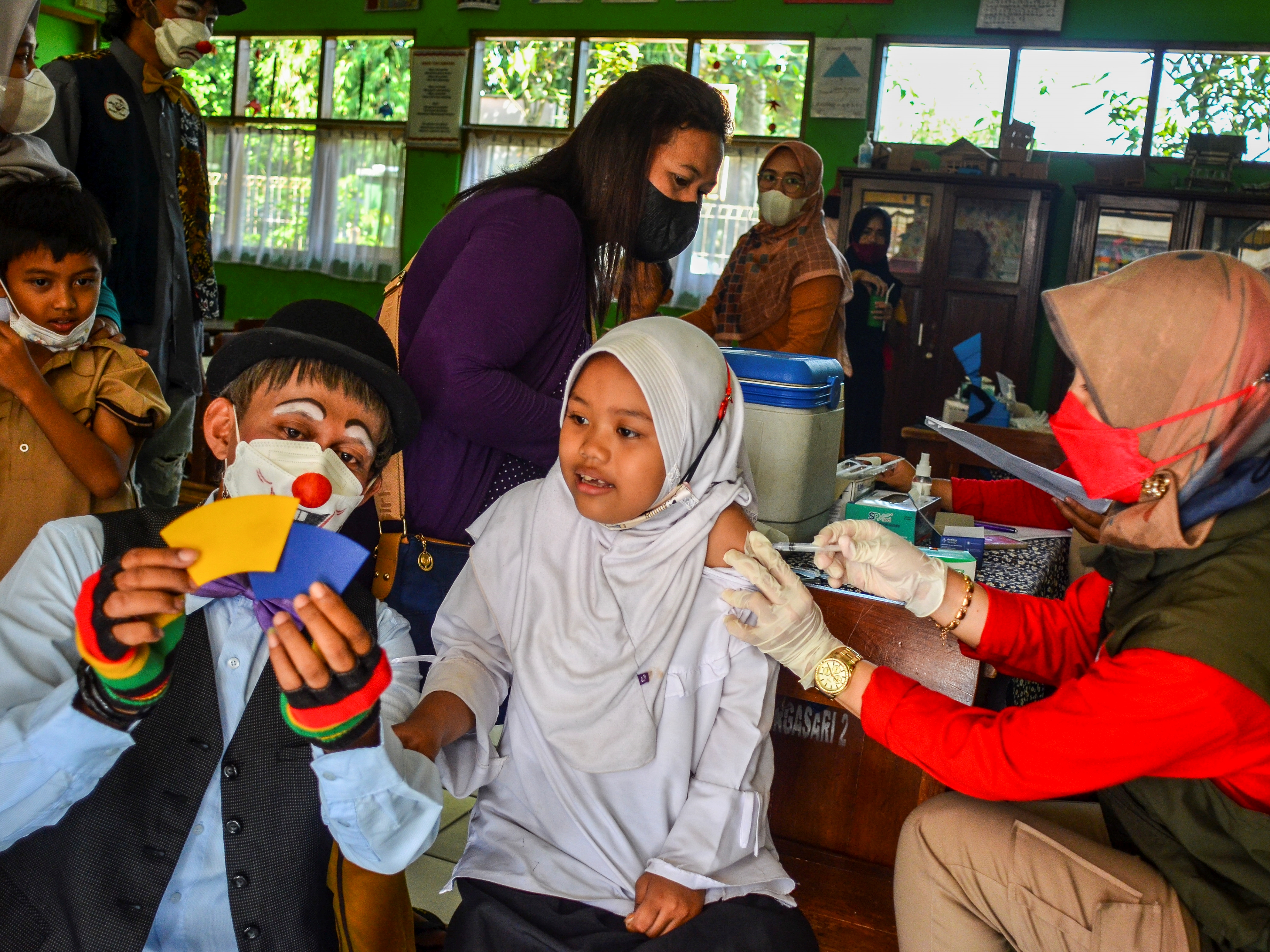 Anggota Komunitas Badut Tasikmalaya memainkan sulap di depan anak saat vaksinasi covid-19 di SDN Argasari, Kota Tasikmalaya.