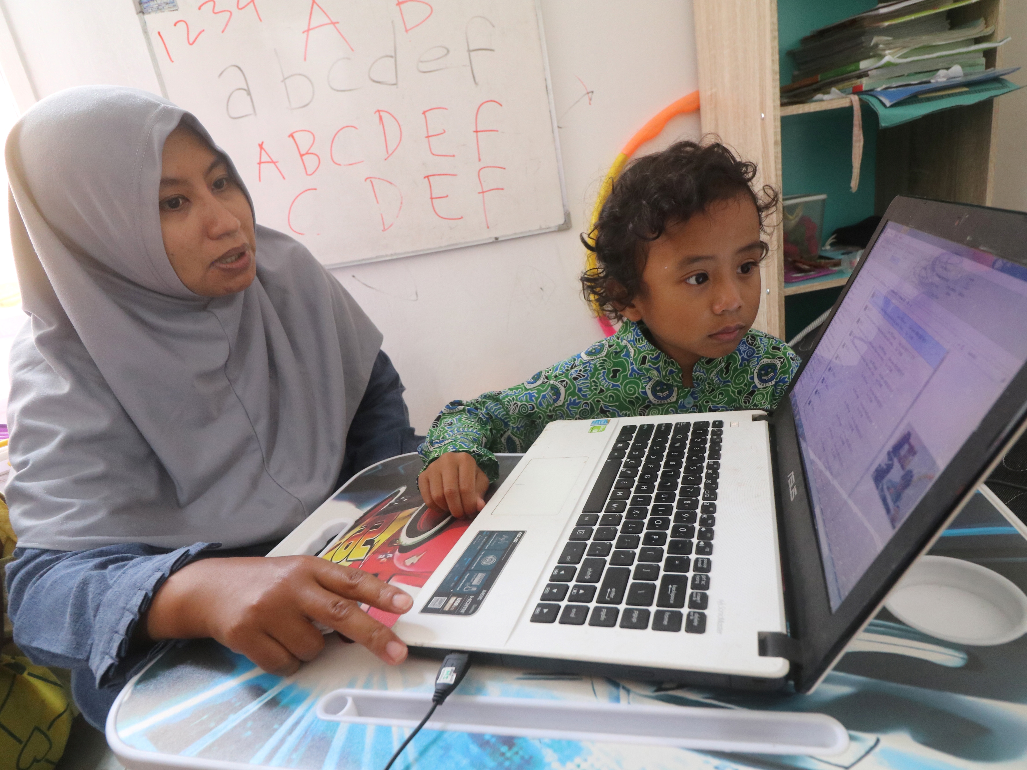 Seorang murid TK dibimbing orangtuanya belajar secara daring di rumah, Kelurahan Ketami, Kota Kediri, Jawa Timur, Rabu (9/2/2022).