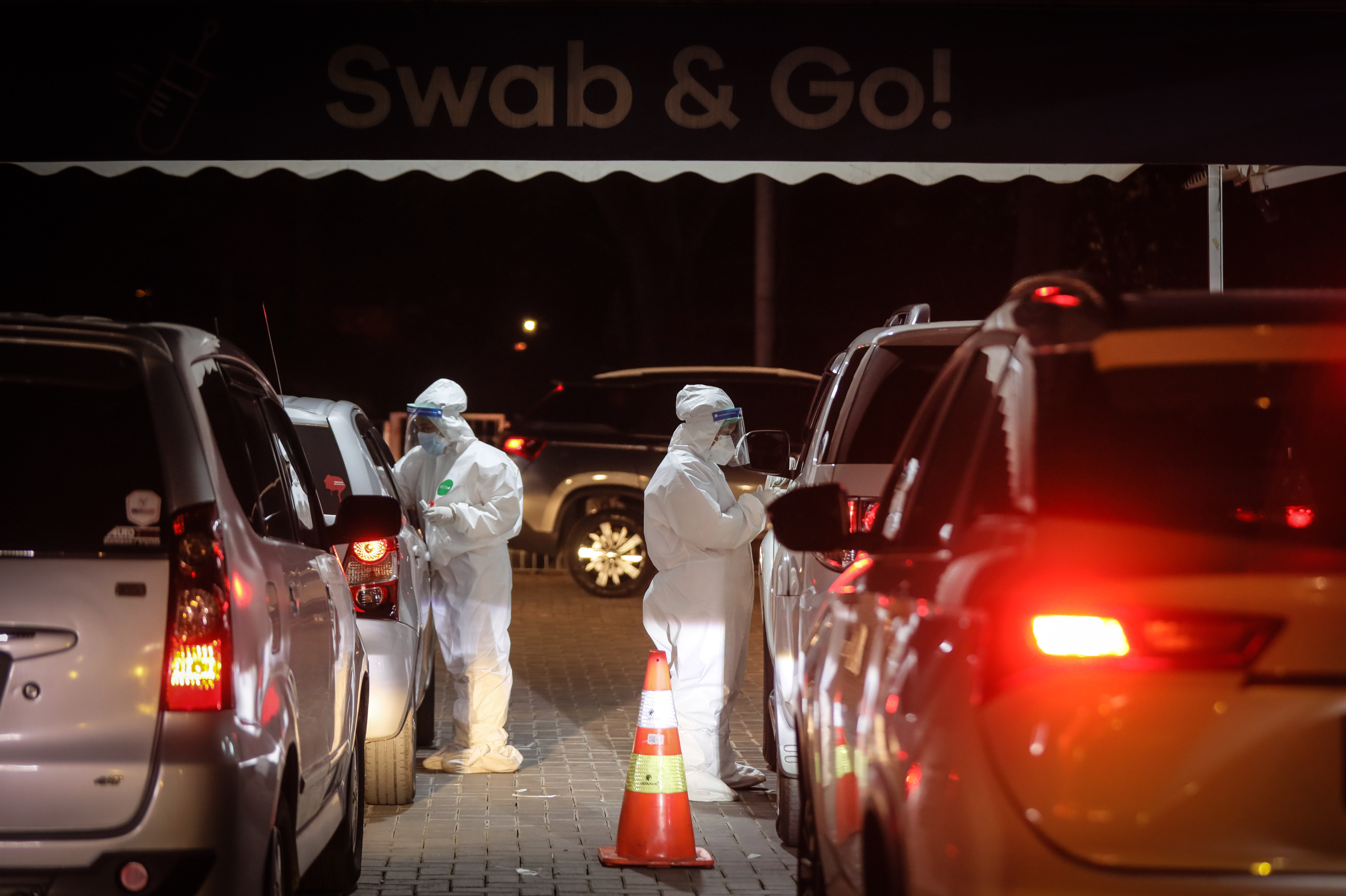 Petugas medis melakukan tes swab PCR warga dari dalam mobil atau drive thru di Swab PCR FastLab Bumame kawasan Kebon Jeruk, Jakarta.