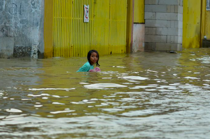 Seorang anak bermain banjir di Perumahan Villa Indah Permai, Bekasi, Jawa Barat, Minggu (16/1).