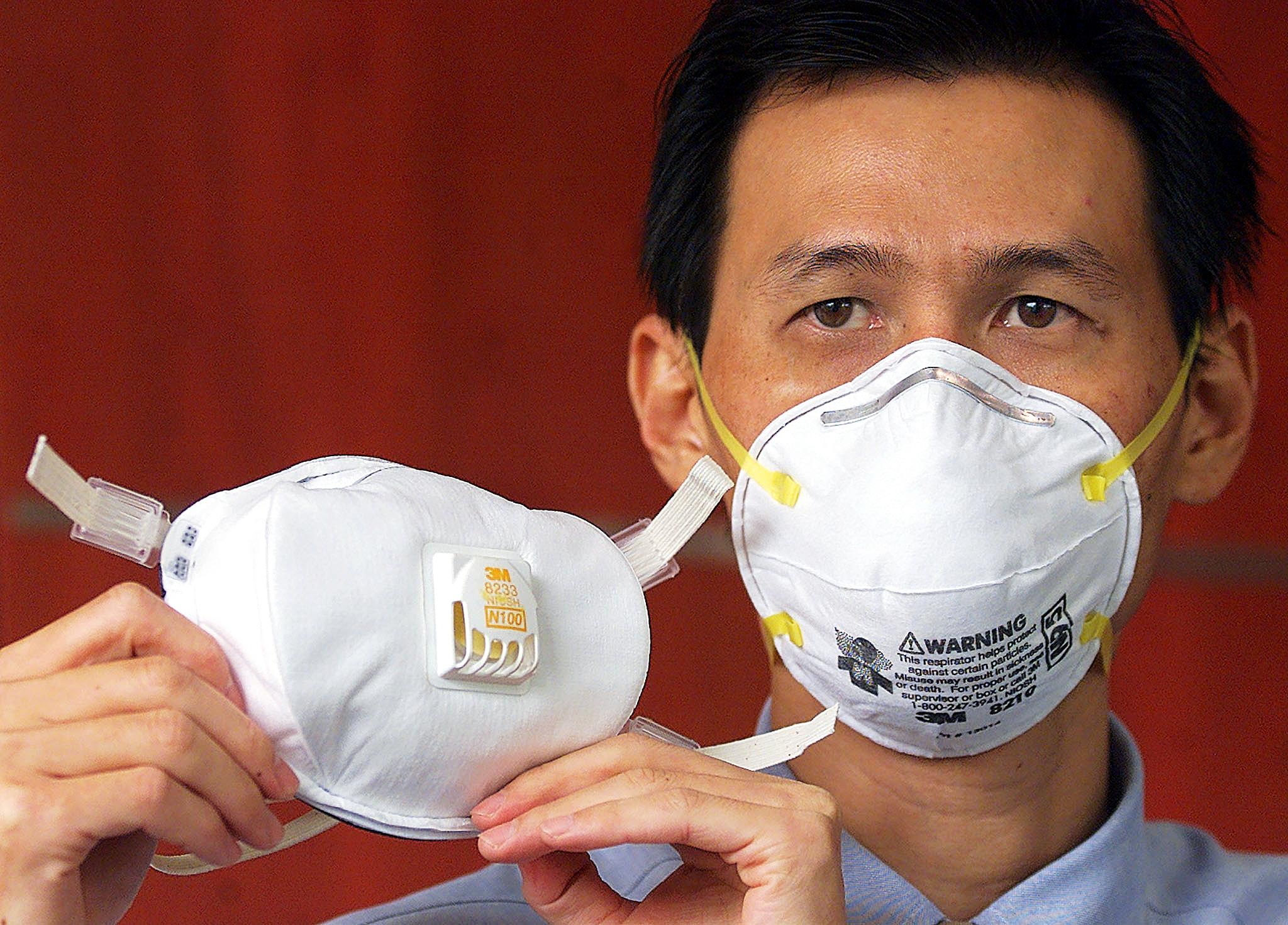 Seorang pria menunjukkan masker dan menggunakan masker tipe N95. 