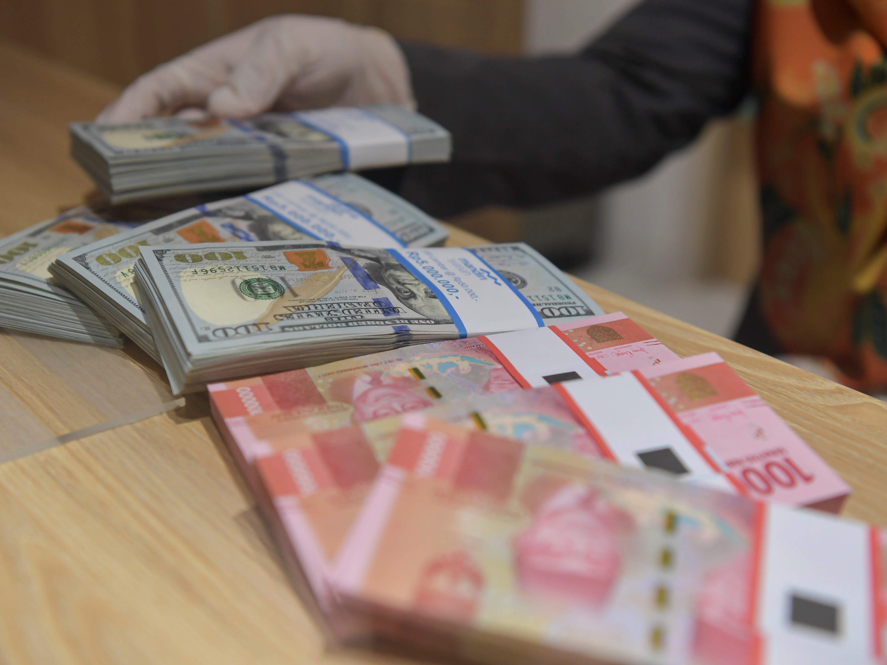 Karyawan menghitung uang rupiah dan dolar AS di Bank Mandiri Syariah, Jakarta.