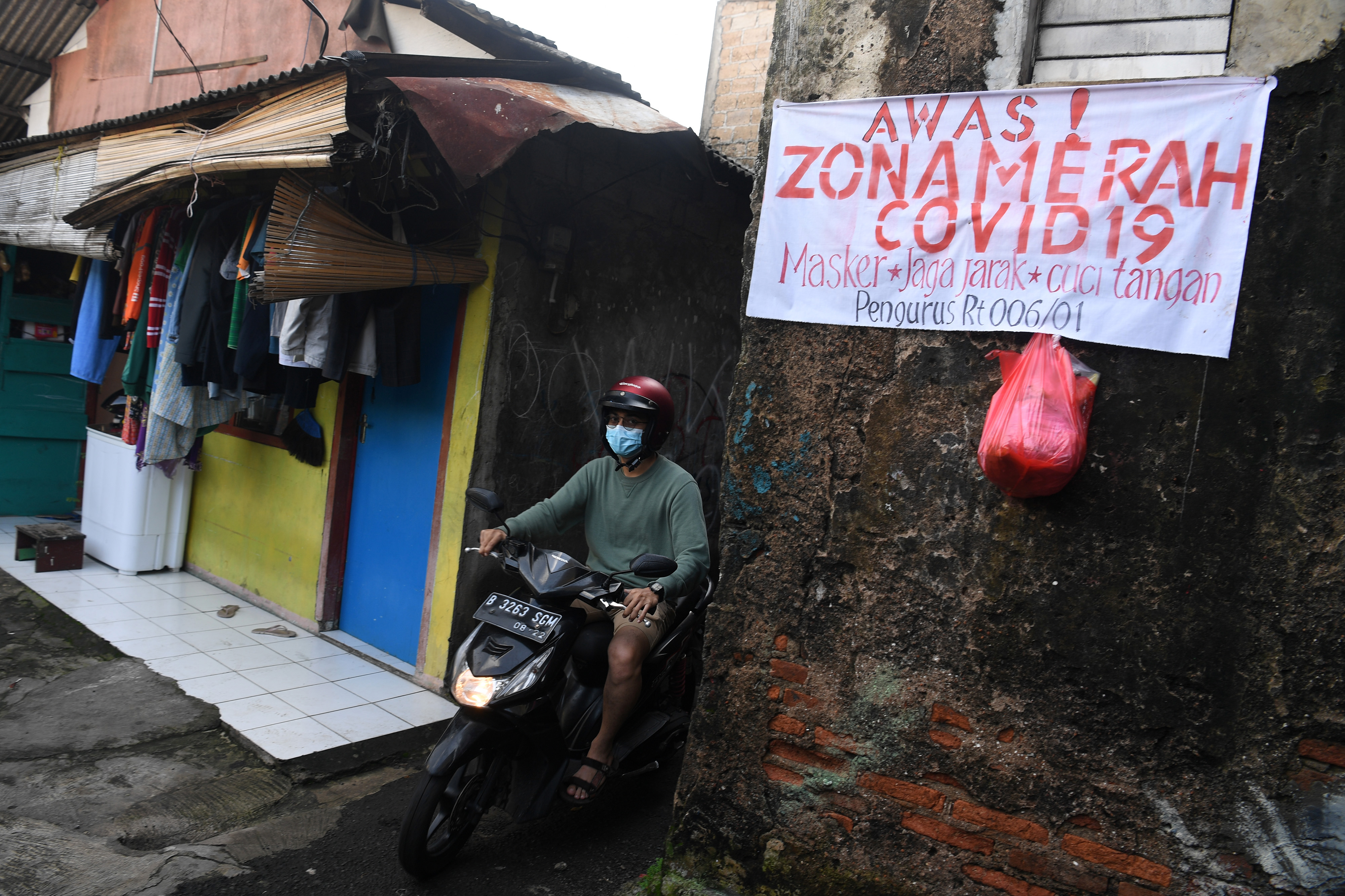 Warga berkendara di zona merah covid-19 di kawasan Gandaria Selatan, Jakarta.