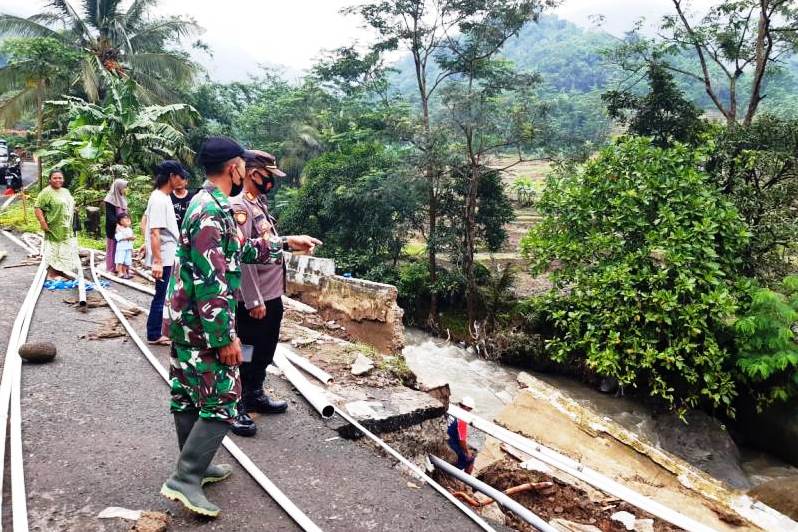 Danramil 14 Banjarharjo Kodim 0713 Brebes (seragam tentara) Kapten Cpl. A. Chaerul Huda meninjau ruas jalan yang longsor.