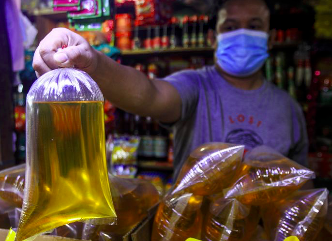 Pedagang menunjukkan minyak goreng curah.