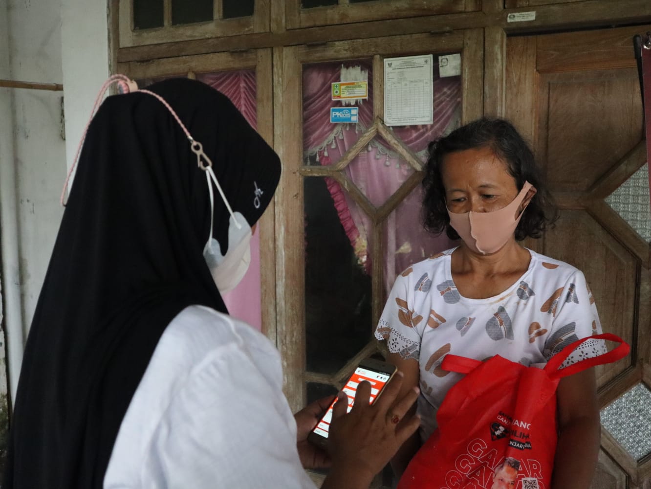 Relawan menggunakan aplikasi 'Sahabat Ganjar' saat memberikan bantuan sembako di Jawa Timur.   