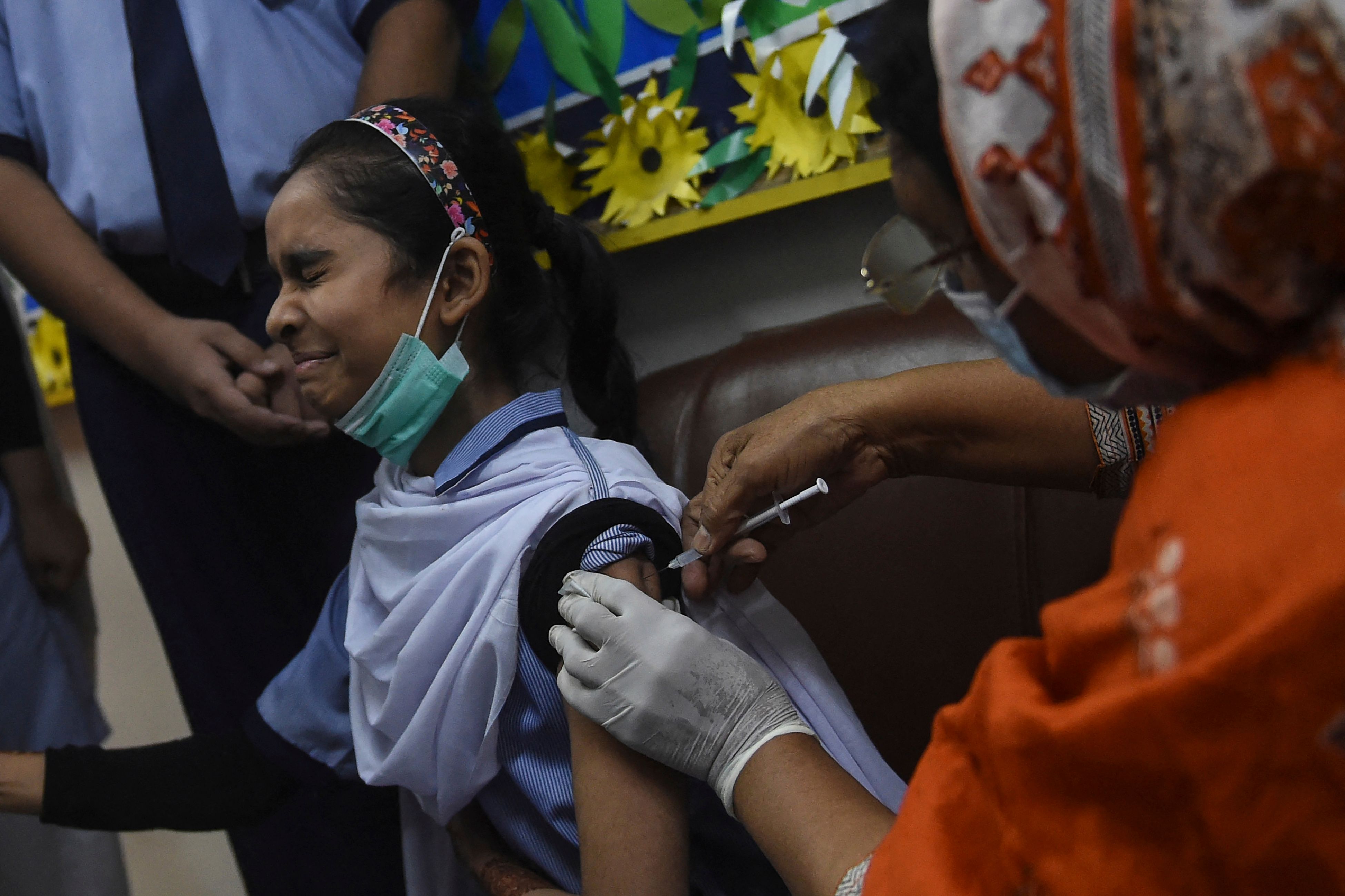 Ilustrasi.   Seorang nakes tengah menyuntikan vaksin Pfizer kepada seorang pelajar Pakistan.