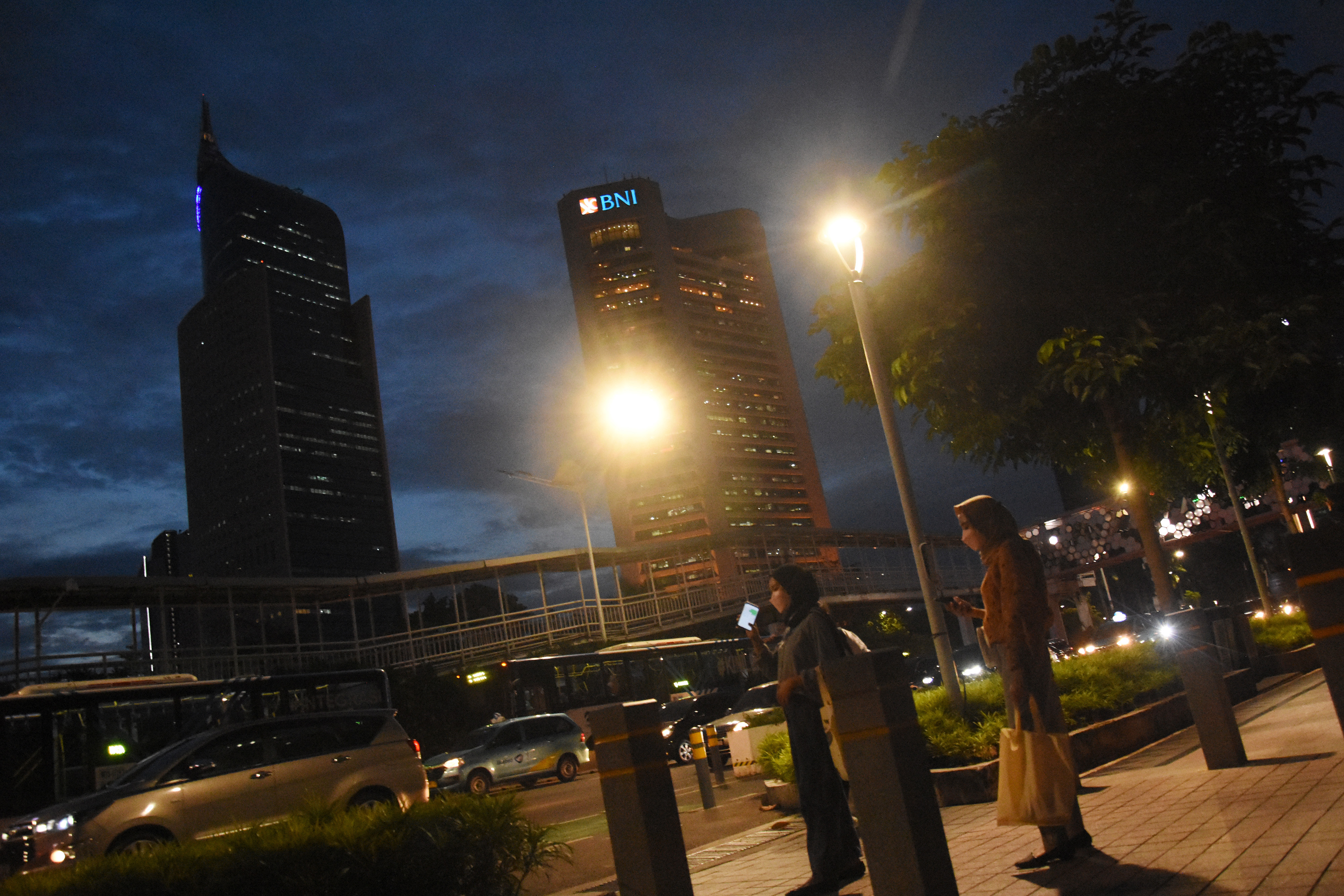 Pekerja menunggu kendaraan saat jam pulang kerja di kawasan Dukuh Atas, Jakarta.