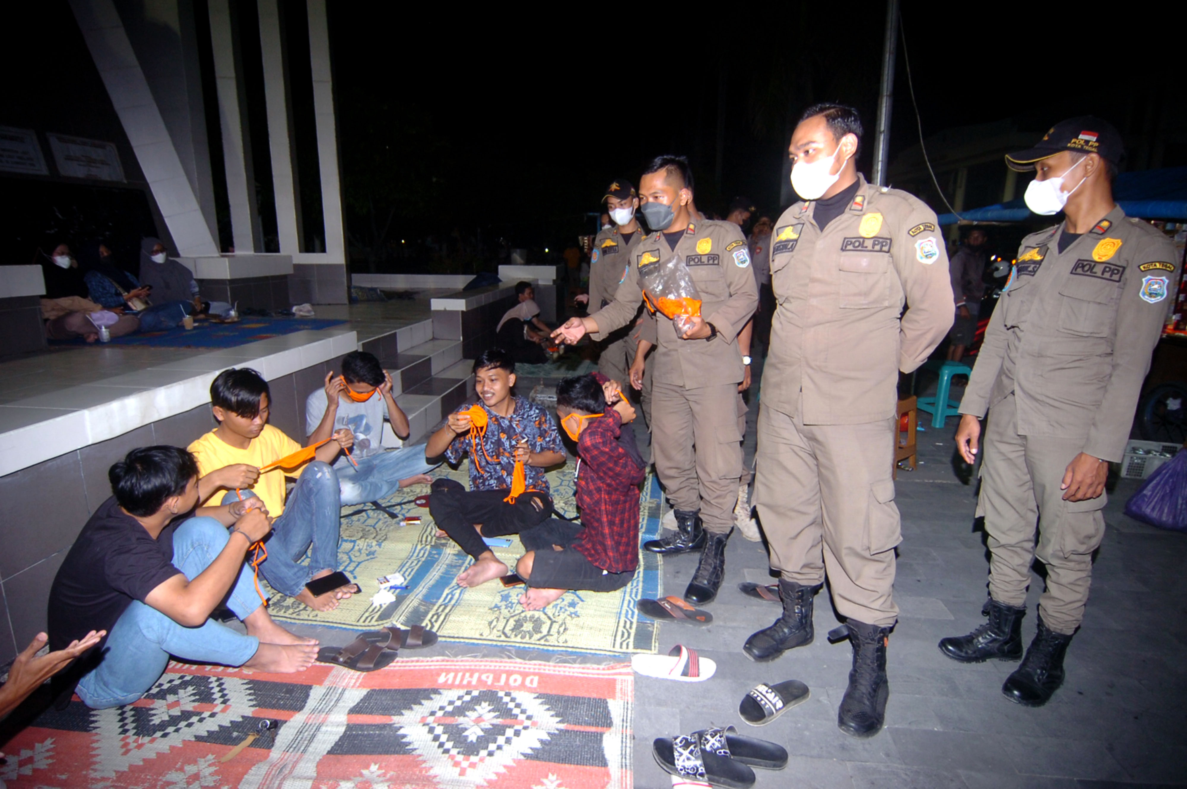 Personel Satpol PP membagikan masker saat razia protokol kesehatan di Tegal, Jawa Tengah, Rabu (5/1/2022) malam. 