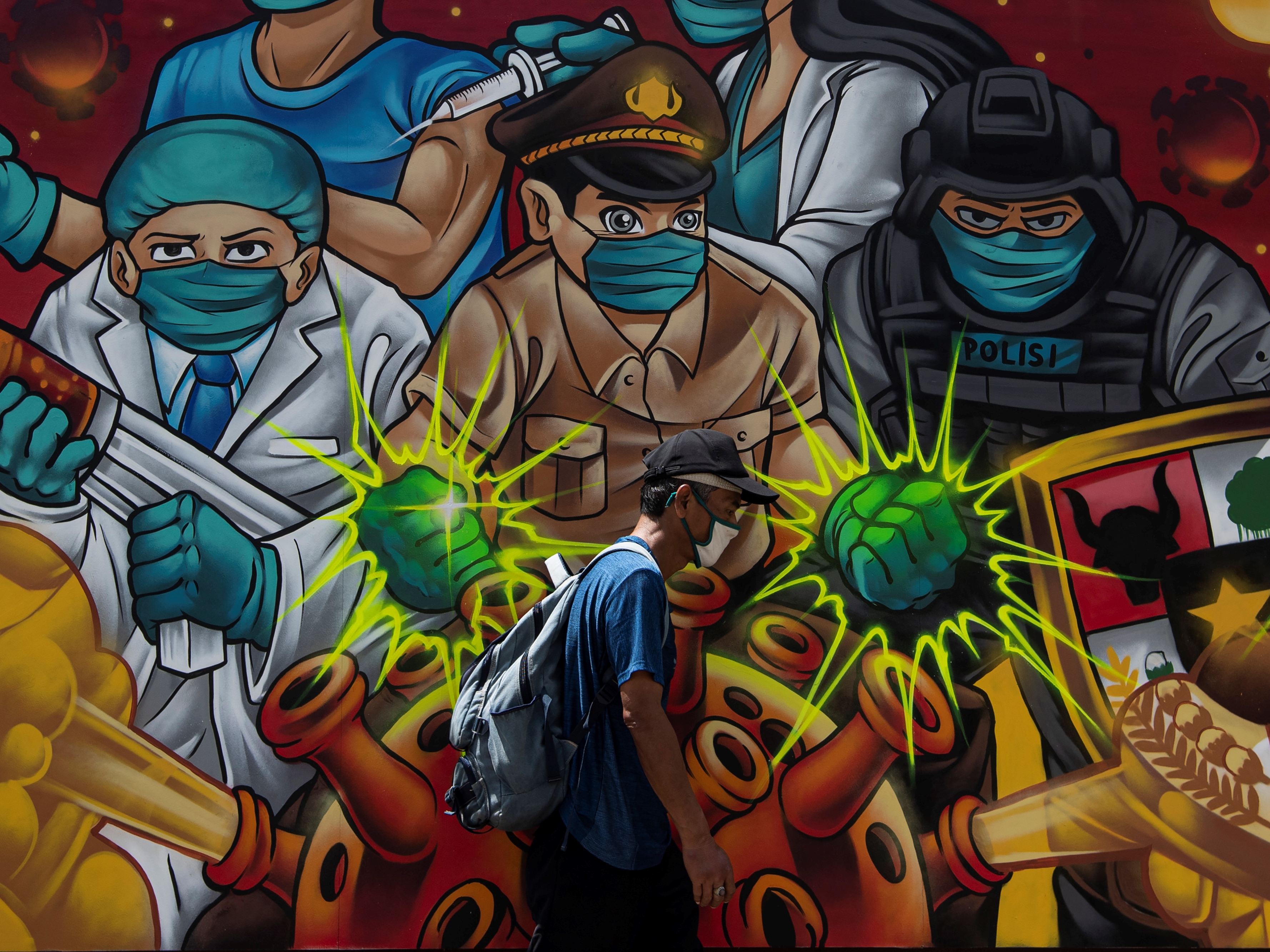 Warga melintas di depan tentang mural covid-19 di Jakarta, Selasa (2/11/2021).