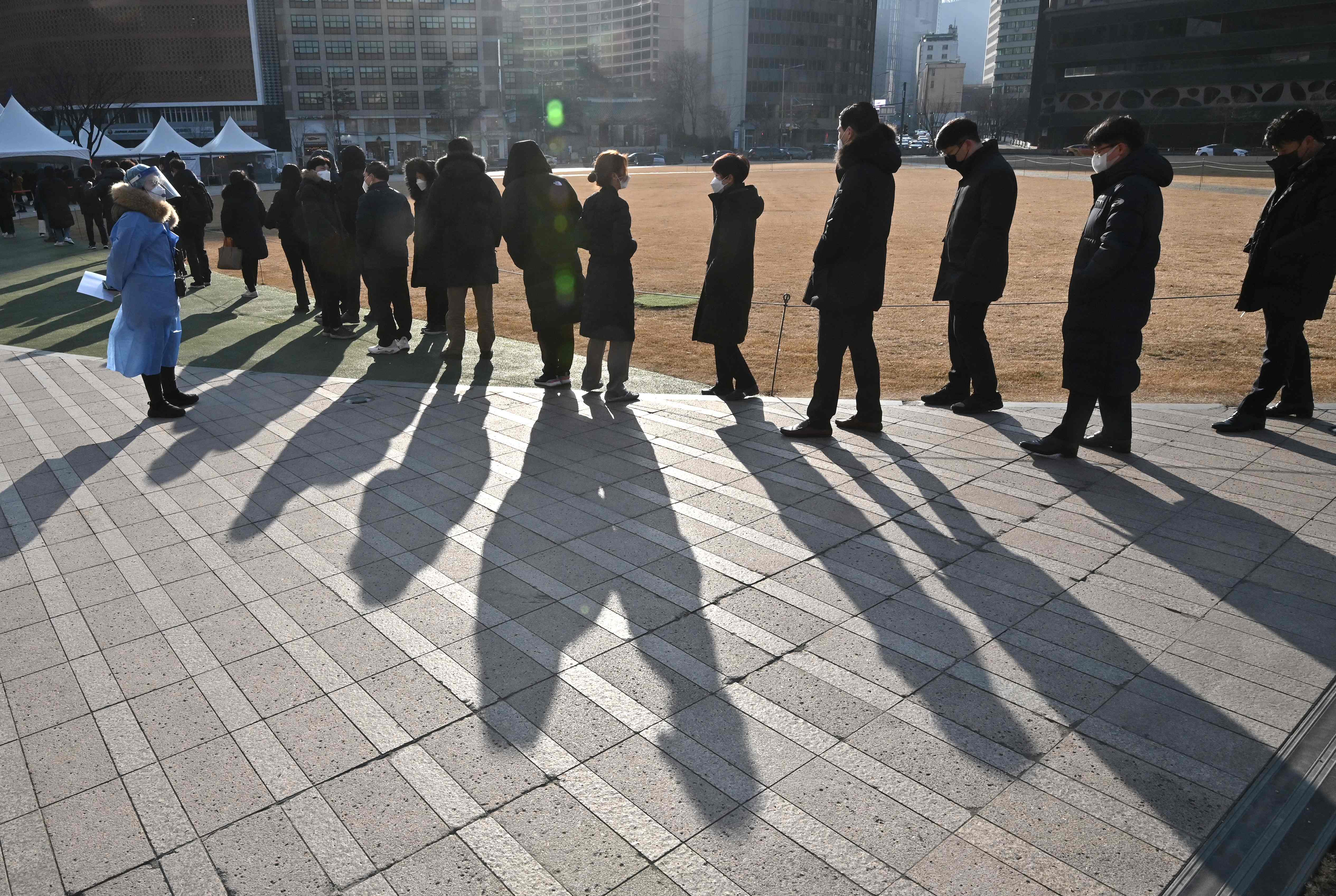 Seorang petugas yang mengenakan APD mengawasi warga yang mengantre untuk menjalani tes covid-19 di Seoul, Korsel.