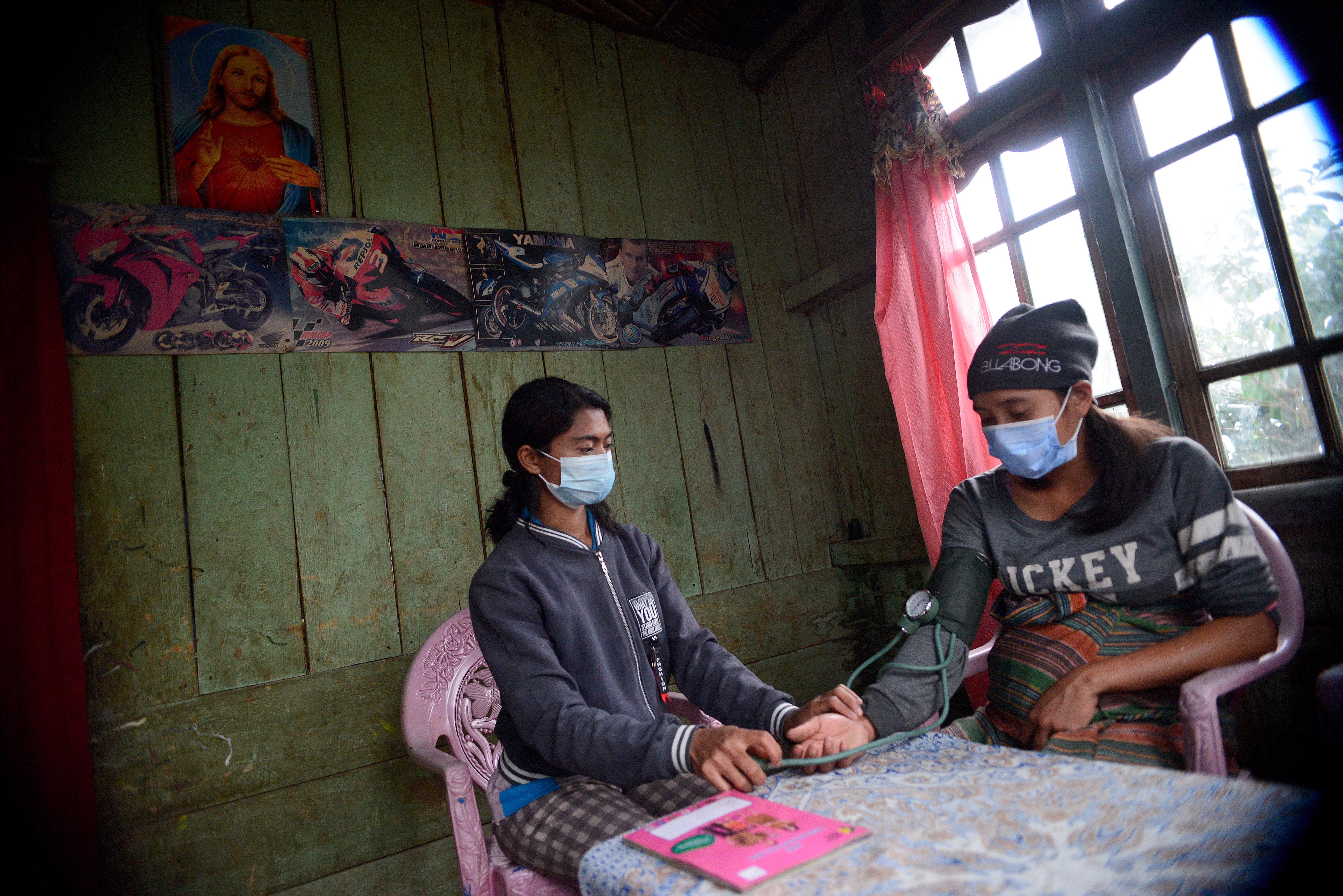 Bidan Ellen (kiri) melakukan kunjungan untuk memeriksa kondisi kesehatan ibu hamil di Desa Colol, Manggarai Timur, Nusa Tenggara Timur.