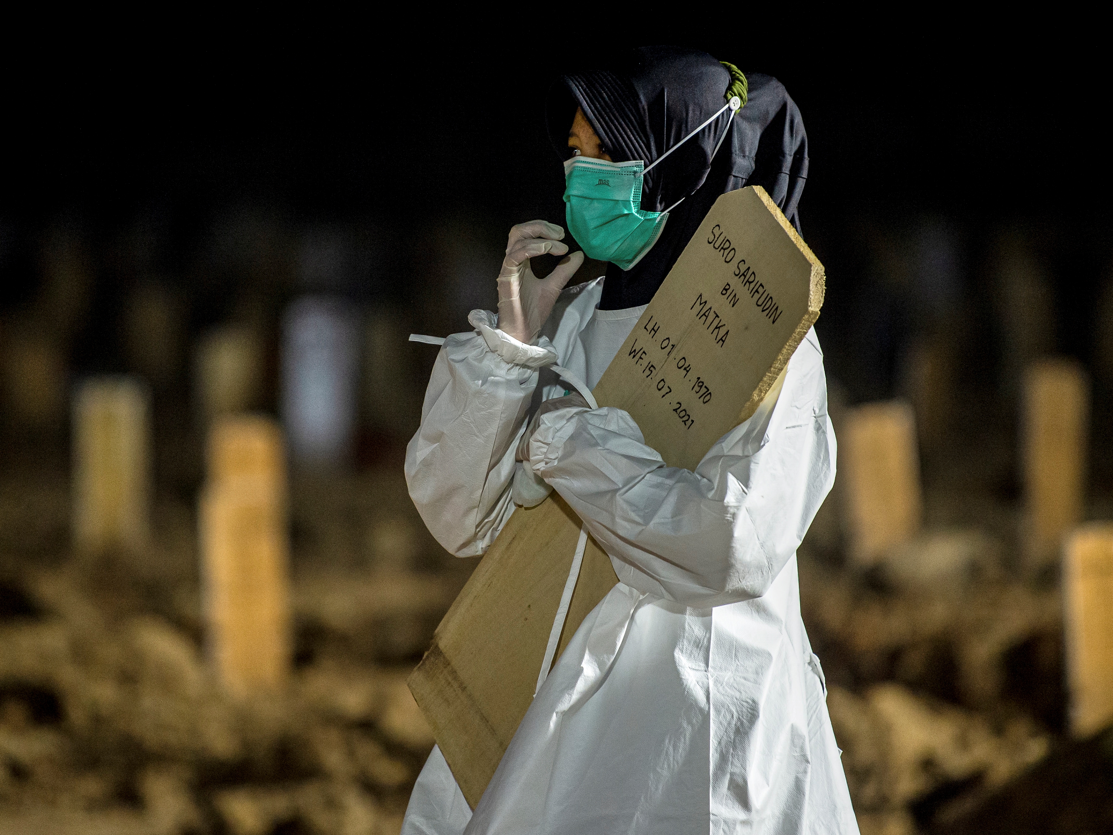 Seorang perempuan membawa nisan di area pemakaman khusus covid-19 di TPU Rorotan, Cilincing, Jakarta Utara, Kamis (15/7/2021).