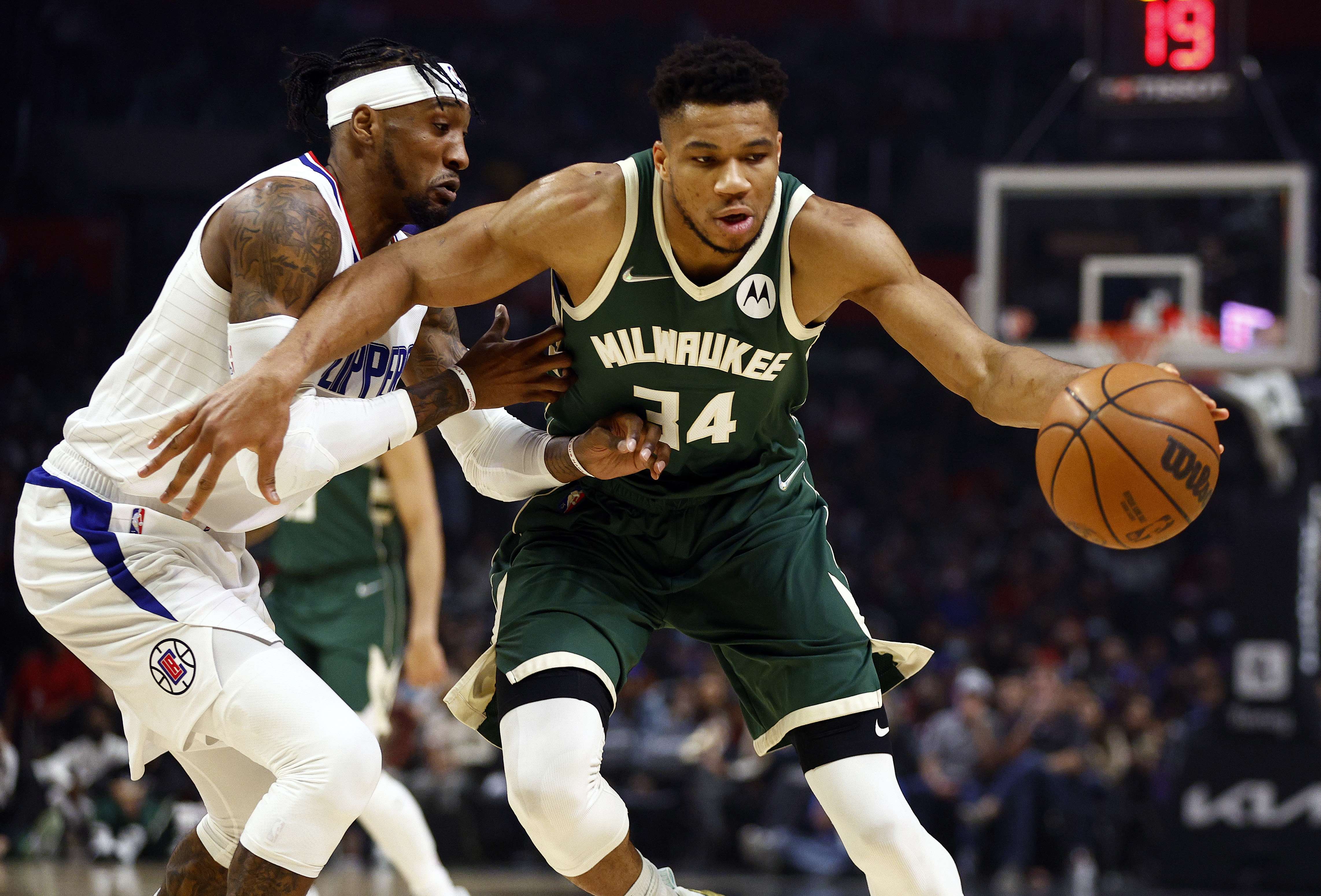 Giannis Antetokounmpo (kanan) dari Milwaukee Bucks menggiring bola dengan dihalangi pemain LA Clippers, Robert Covington. 