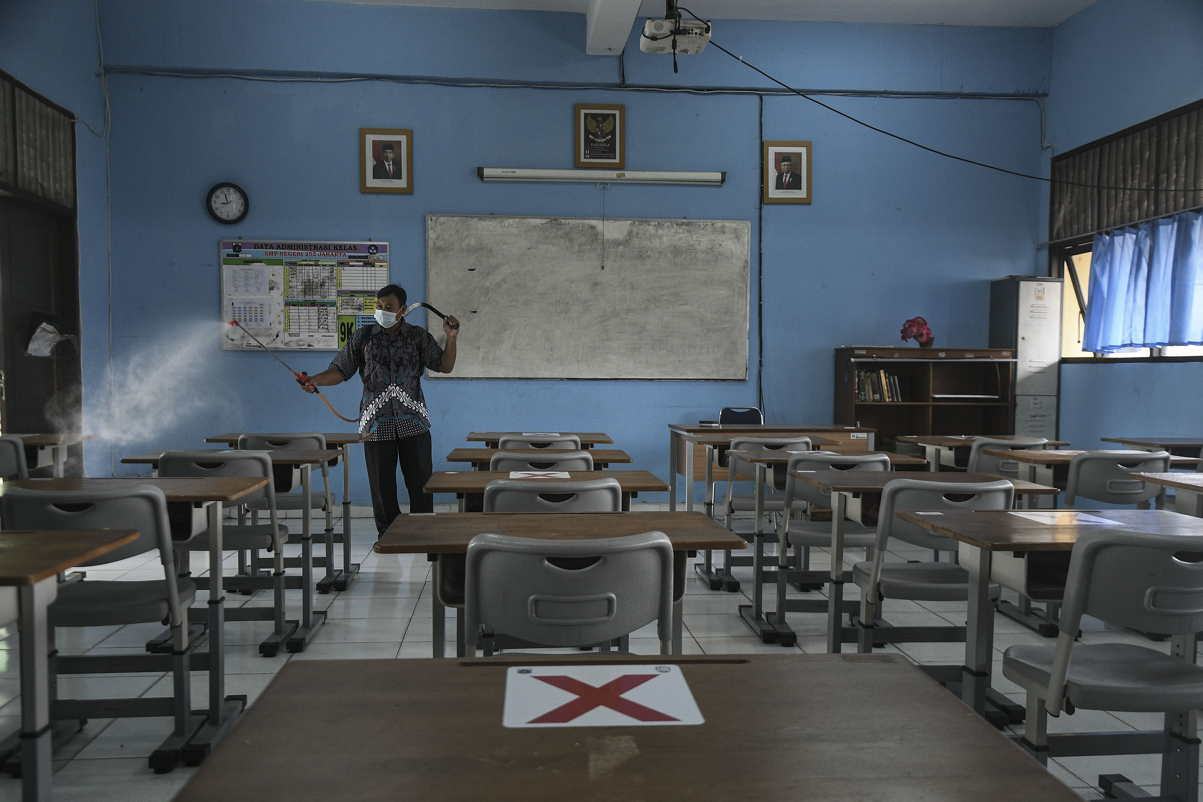 Petugas menyemprotkan disinfektan di ruang kelas SMPN 252, Jakarta Timur, Jakarta.