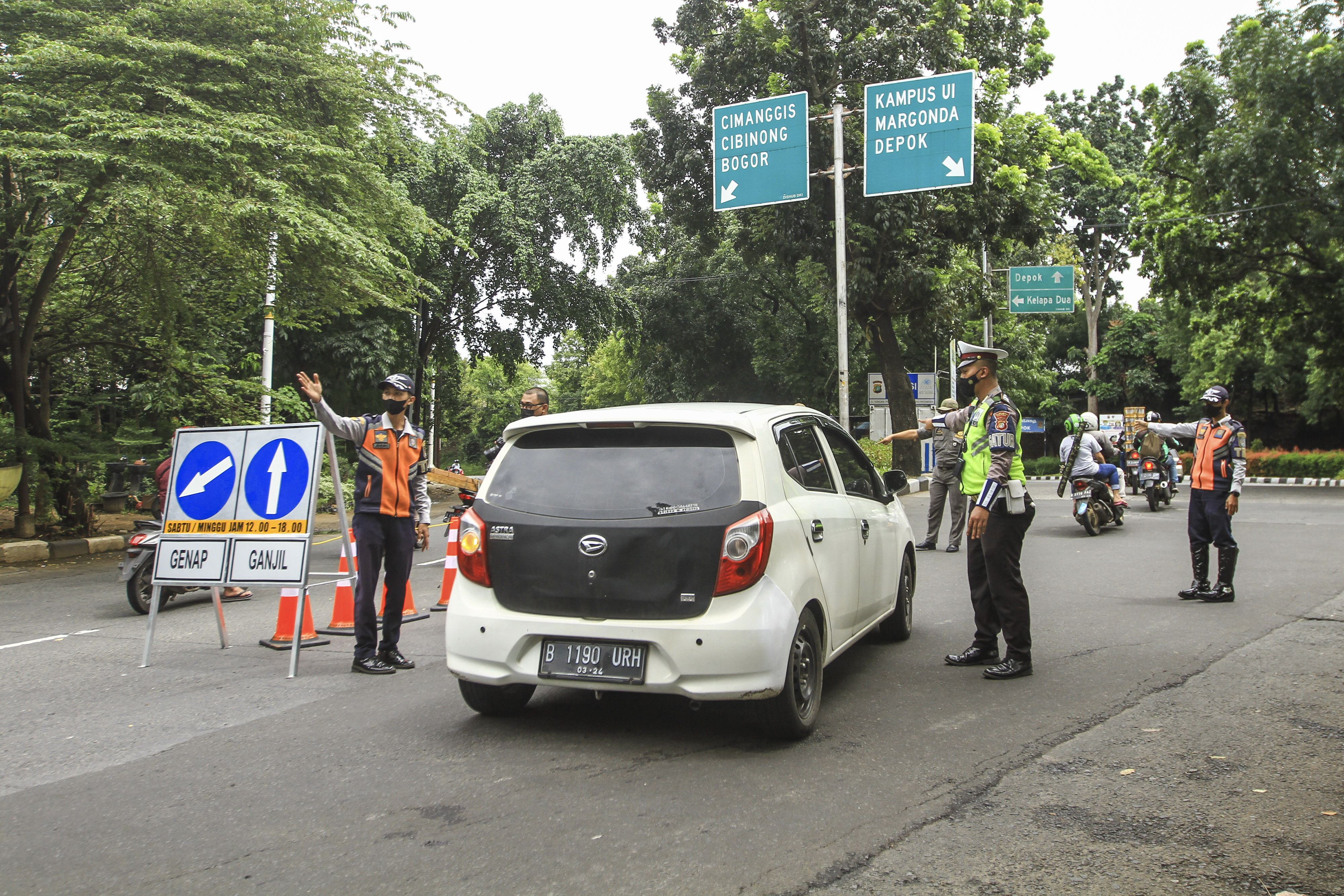Sejumlah petugas memeriksa kendaraan roda empat saat uji coba ganjil - genap di Jalan Margonda Raya, Depok, Jawa Barat, Minggu (5/12/2021)