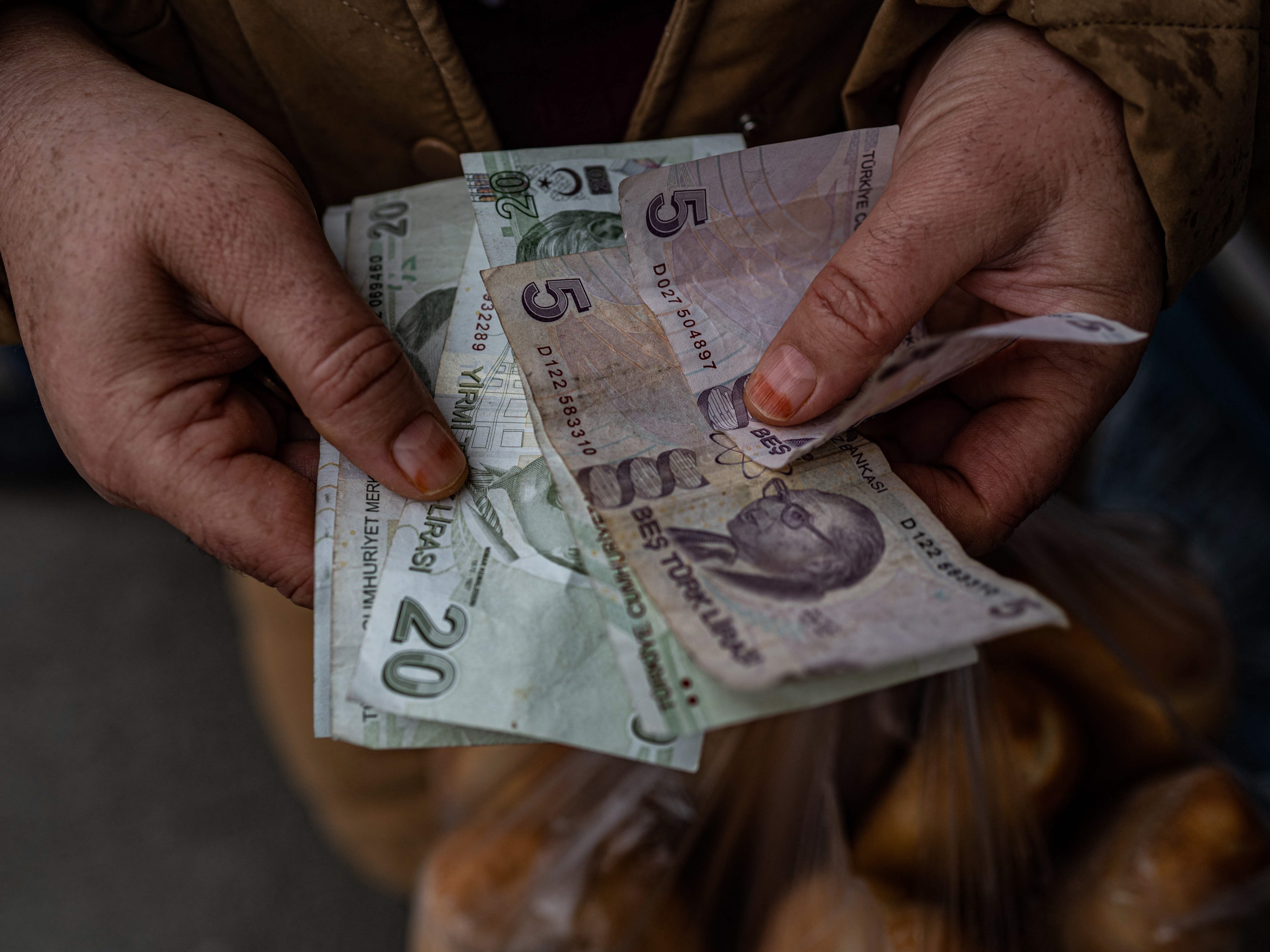 Warga menghitung uang kertas lira Turki di distrik Sultangazi Istanbul, setelah dia membeli roti di toko roti murah Kota Istanbul.