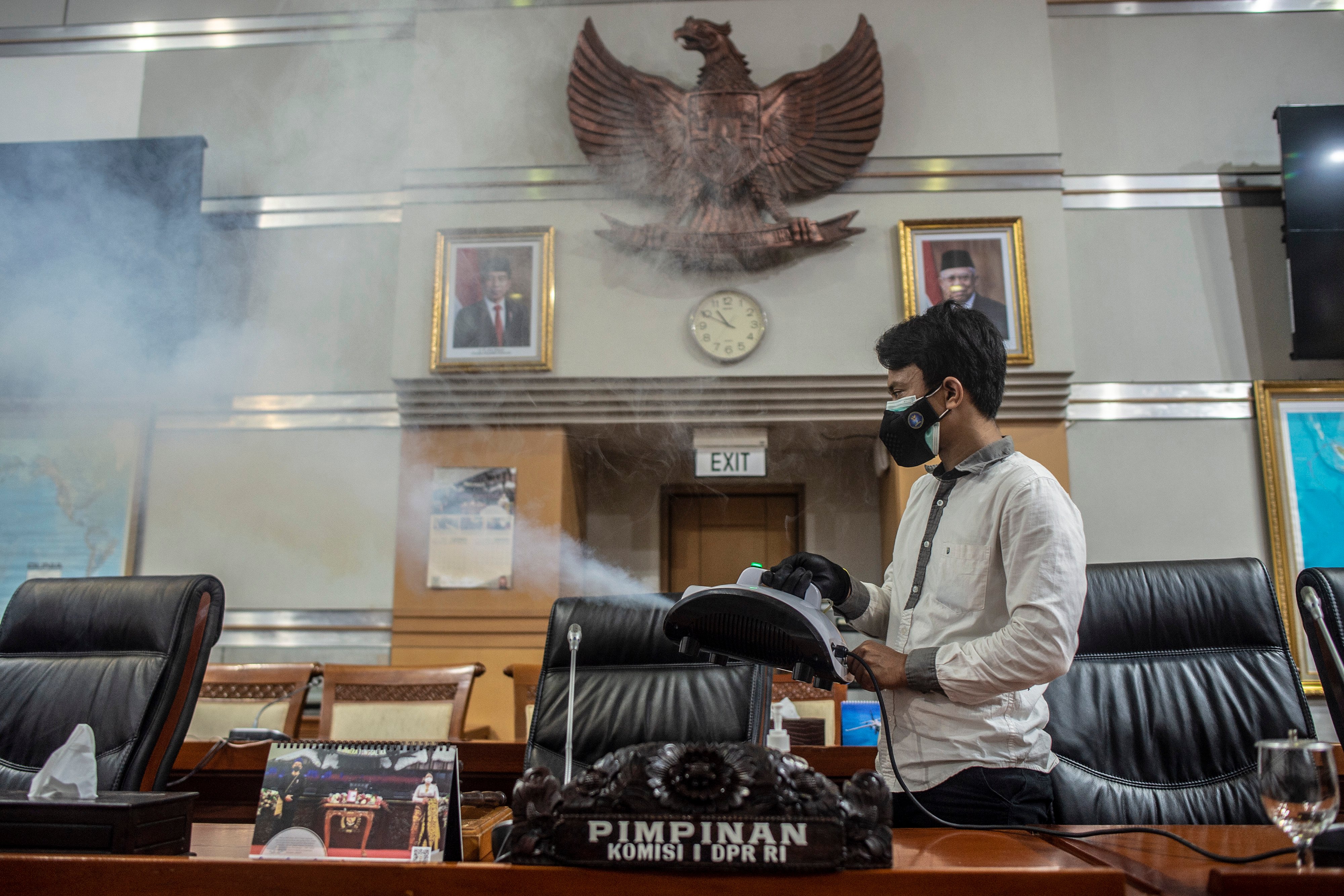 Pegawai DPR menyemprotkan disinfektan ke ruang rapat DPR