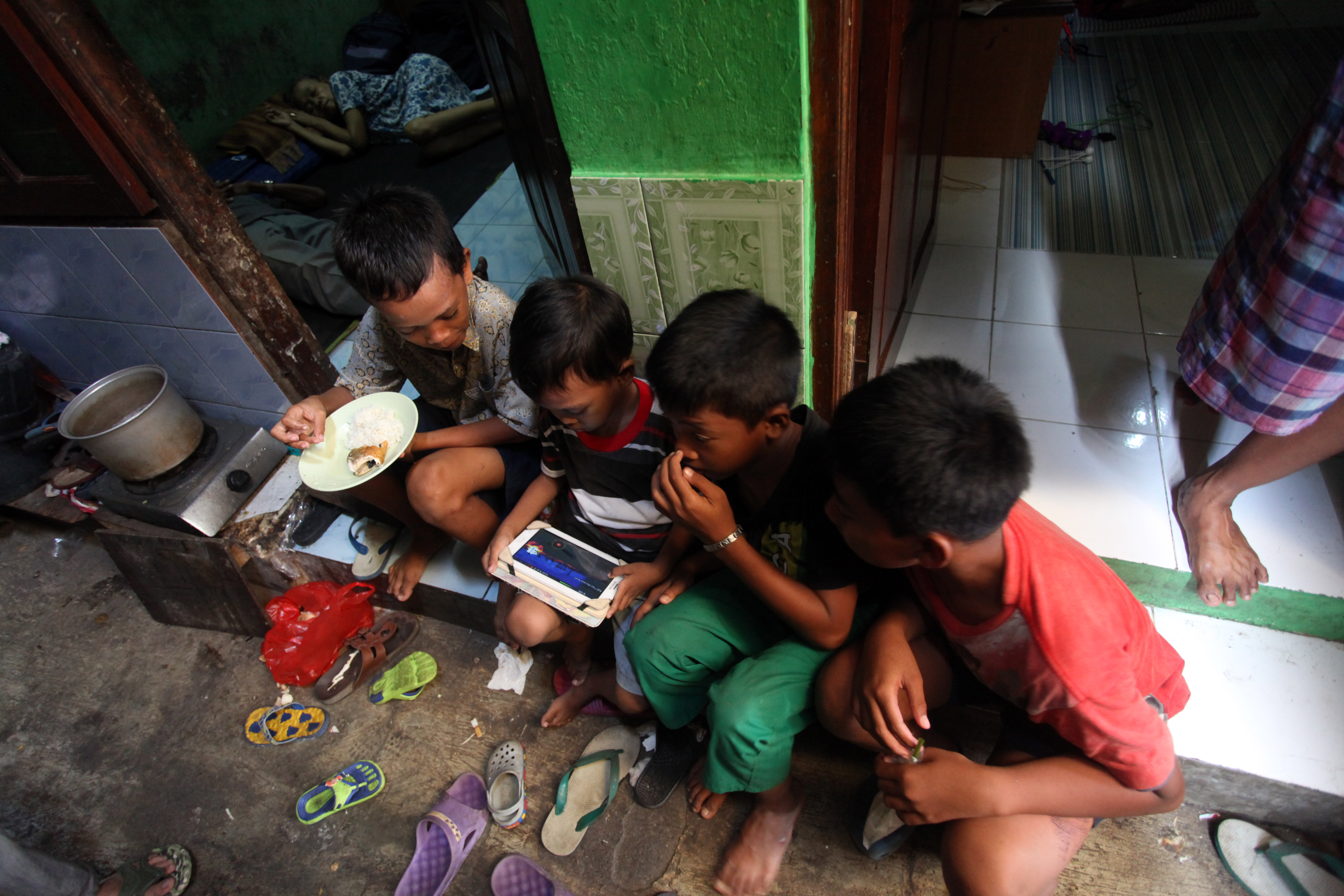 Anak-anak bermain gawai yang terkoneksi internet di permukiman gang sempit di kawasan Kwitang, Jakarta Pusat.
