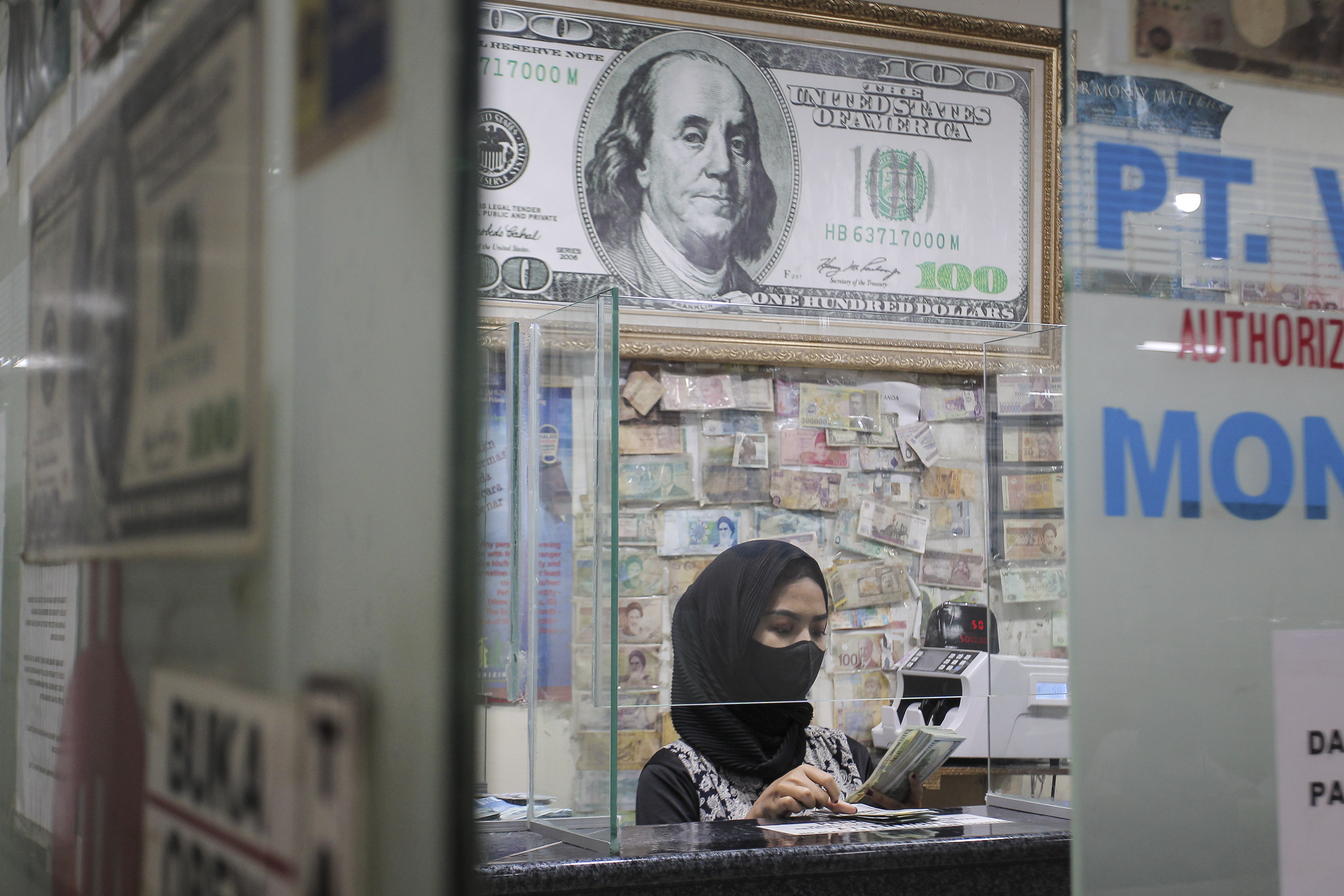 Pekerja menghitung uang dolar AS di salah satu gerai penukaran mata uang di Jakarta, Rabu (5/1).