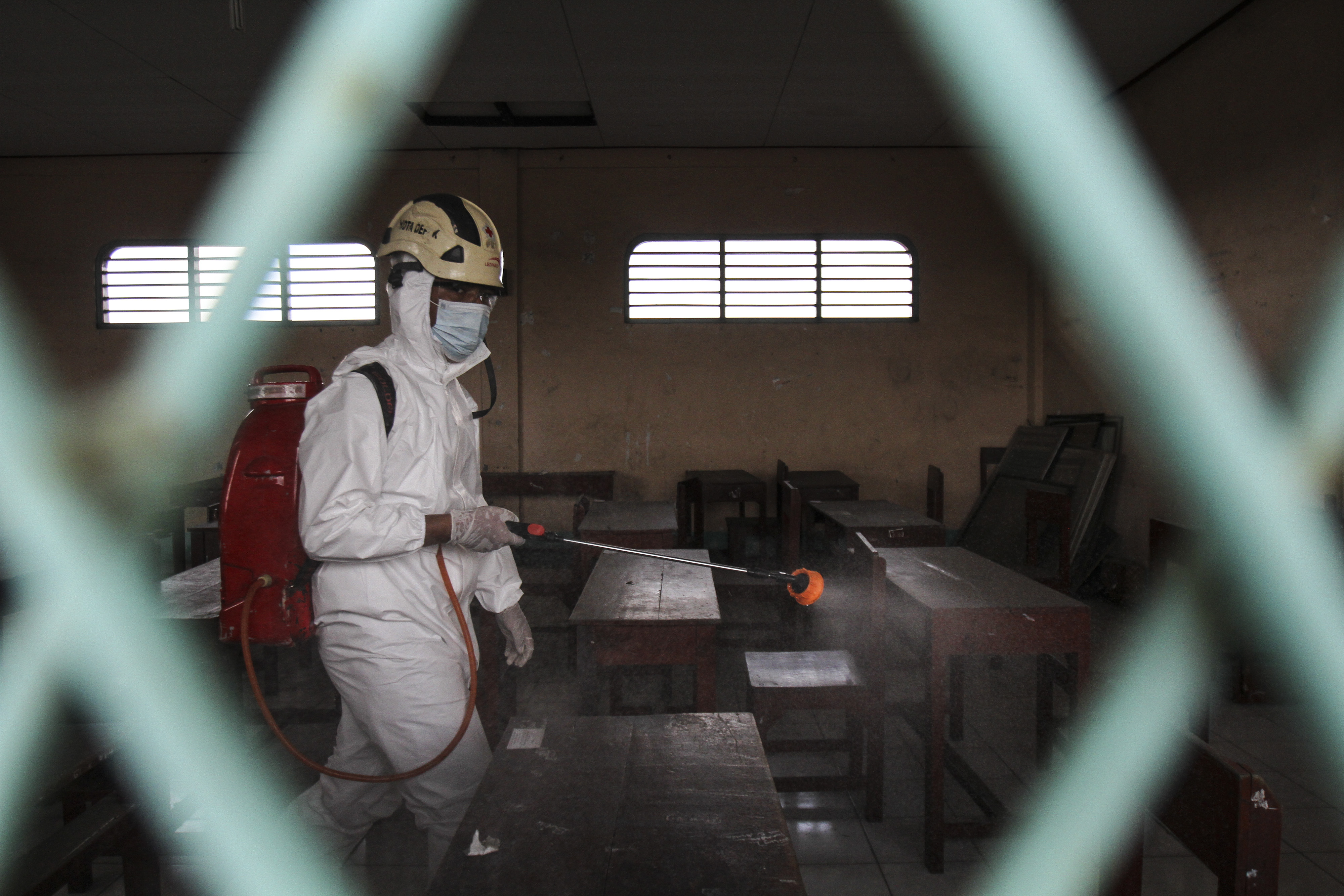 Petugas Palang Merah Indonesia (PMI) menyemprotkan disinfektan di salah satu sekolah di Depok, Jawa Barat
