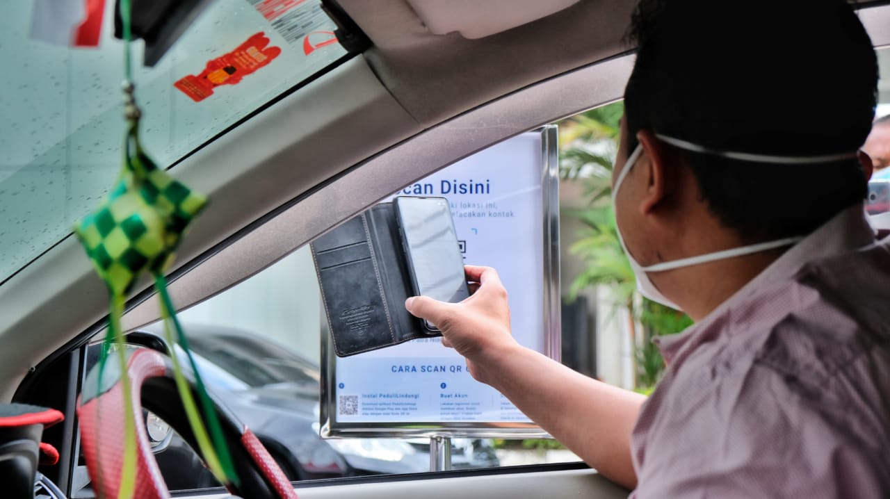 Pengendara tengah melakukan scan aplikasi peduli lindungi.