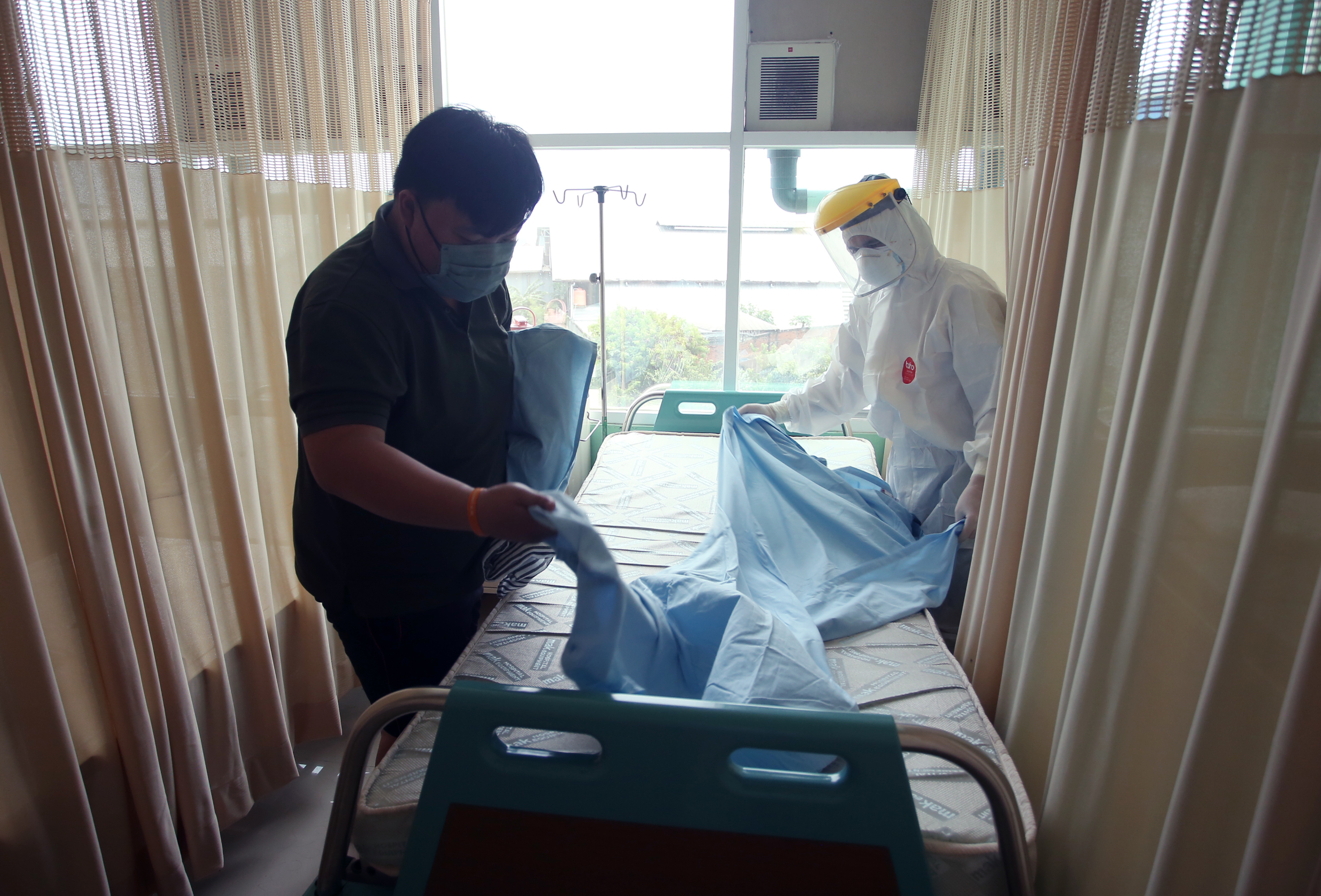 Tenaga kesehatan membantu pasien Covid-19 merapikan tempat tidurnya di salah satu puskesmas di Tangerang, Banten