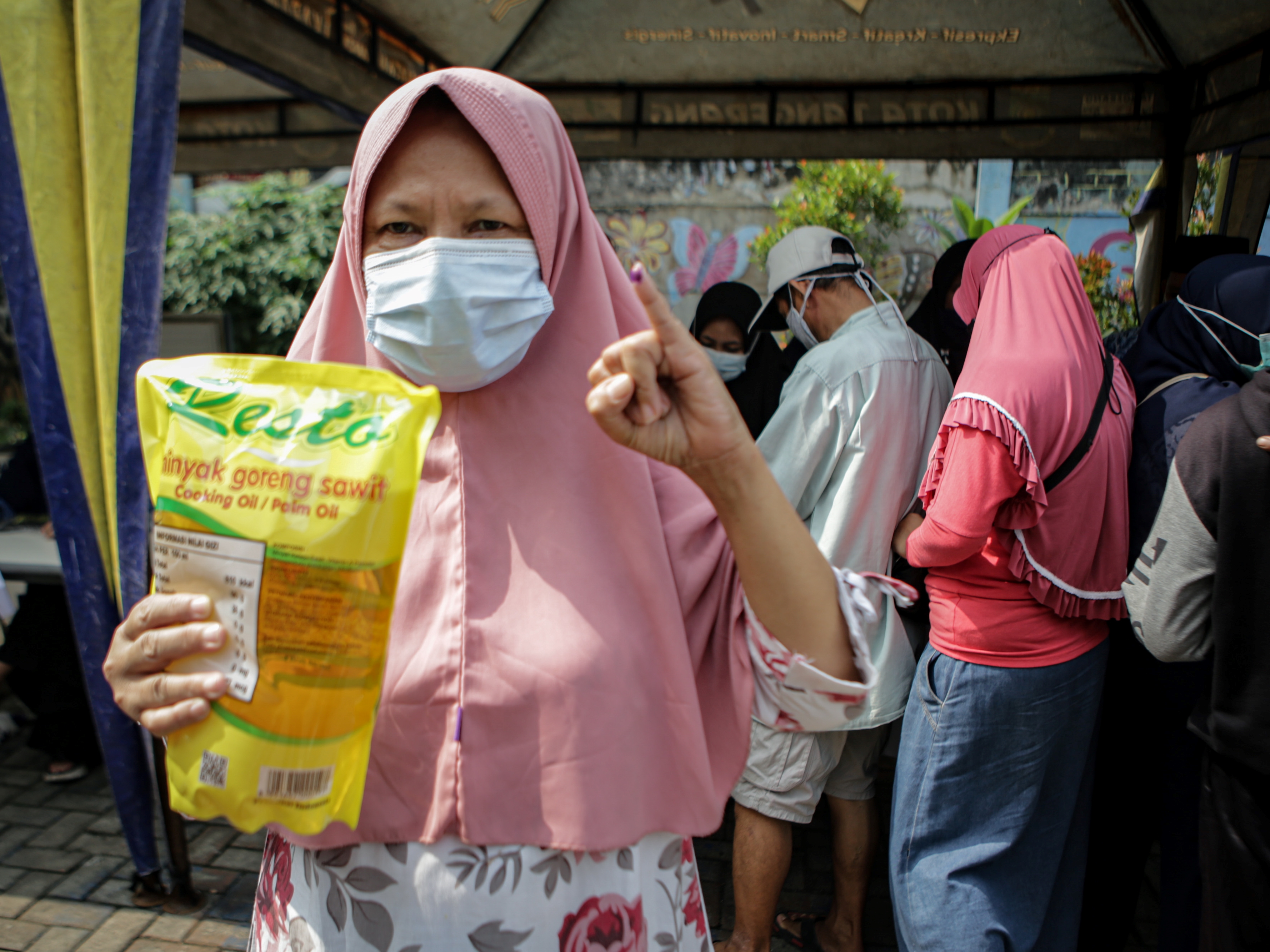Seorang warga menunjukkan minyak goreng yang dibeli saat bazar pangan di Karawaci, Kota Tangerang, Banten, Kamis (17/3/2022). 