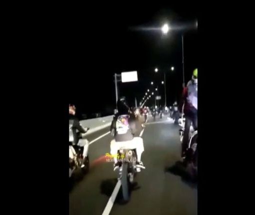 Di dalam video terlihat rombongan pengendara motor yang berkendara di jalan tol sepi pada hari yang gelap.
