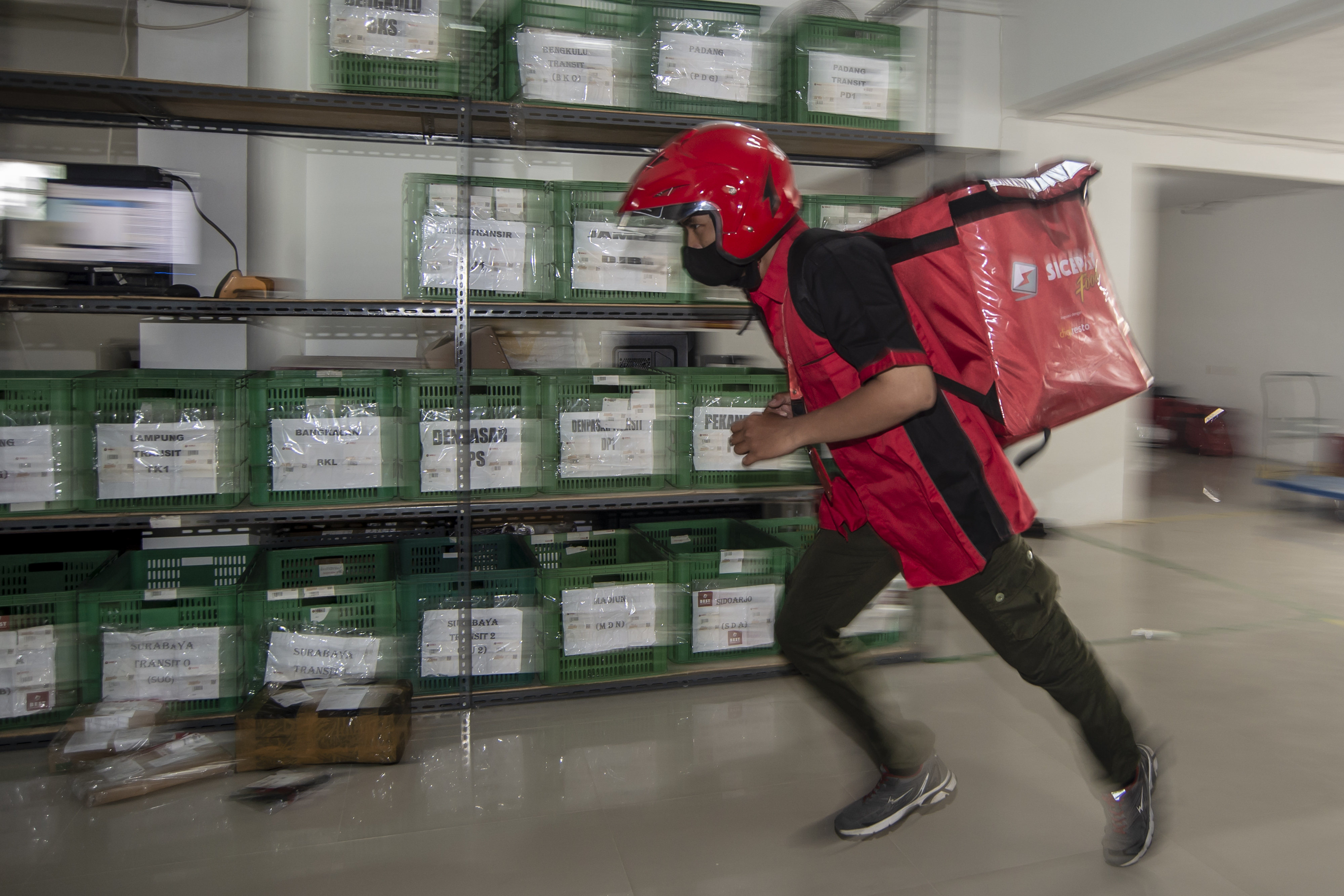 Kurir jasa ekspedisi SiCepat Ekspres berlari untuk melakukan pengiriman di Gerai SiCepat Ekspres Kebon Kelapa, Jakarta, Jumat (11/3/2022).