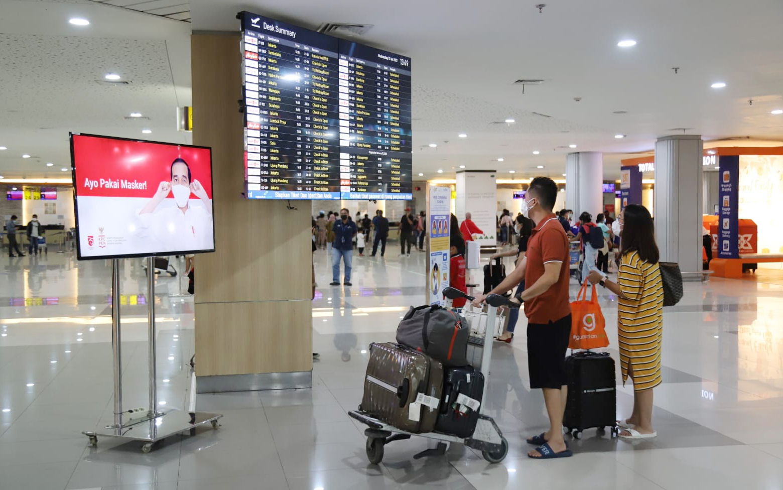 Penumpang melihat jadwal keberangkatan pesawat di Bandara I Gusti Ngurah Rai, Bali.