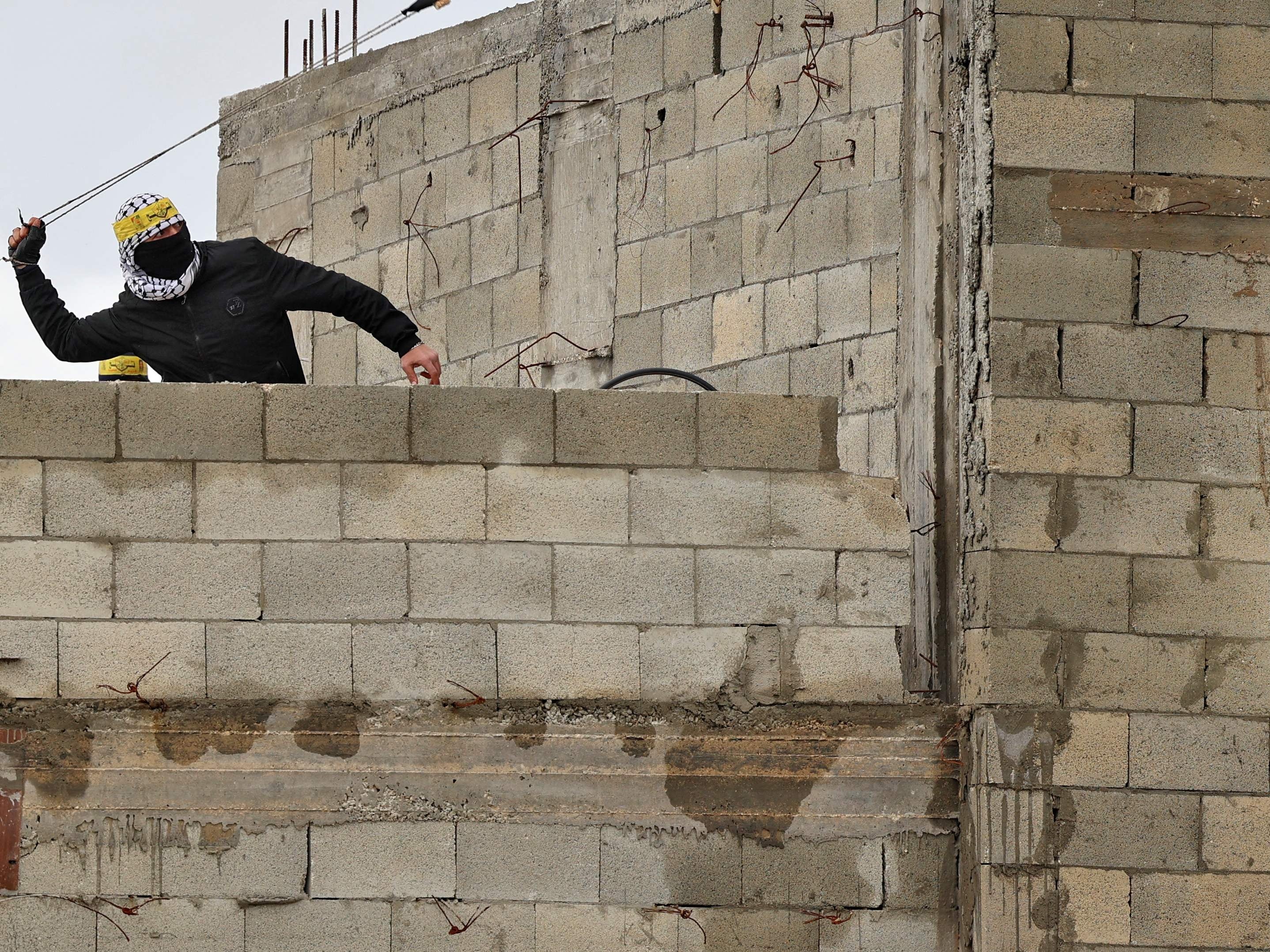 Seorang pemuda Palestina melemparkan batu dari atap ke arah pasukan keamanan Israel selama konfrontasi dengan mereka, 11 Maret 2022.