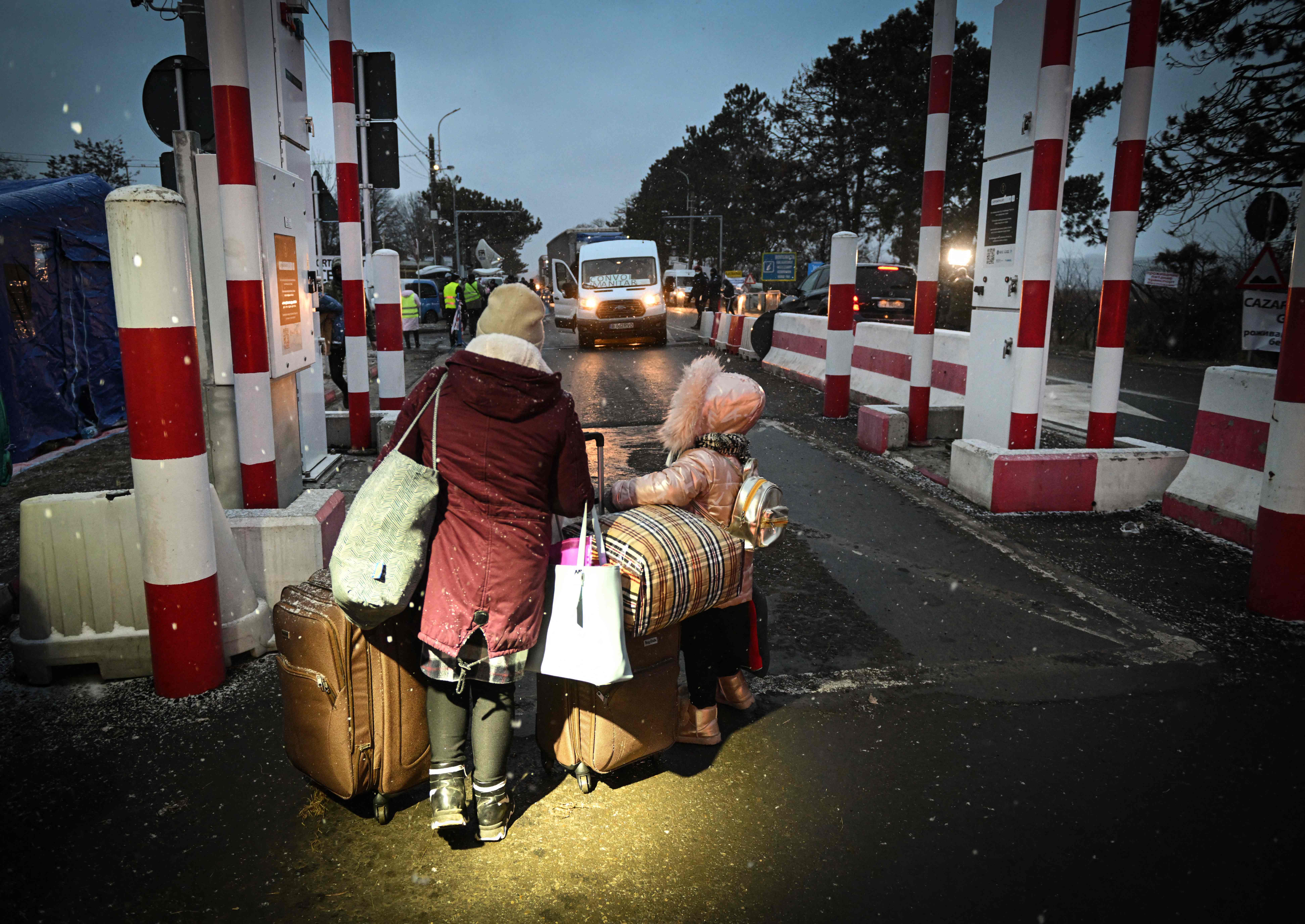 Seorang ibu dan anaknya berjalan untuk memasuki di Siret, Rumania yang berperbatasan dengan Ukraina, Kamis (24/2). 