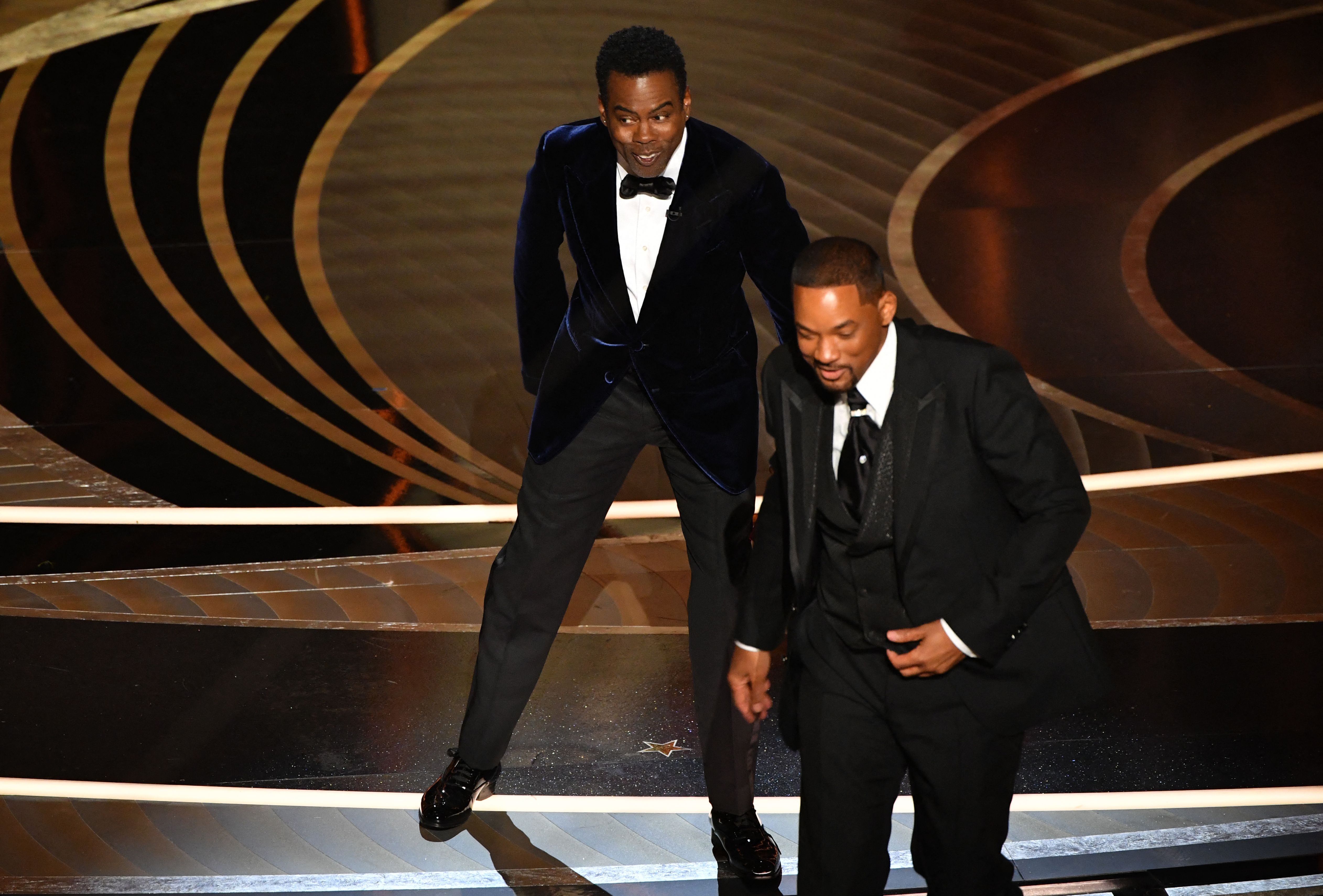 Chris Rock (kiri) dan Will Smith (kanan) pascainsiden penempelengan di panggung live Oscar 2022.