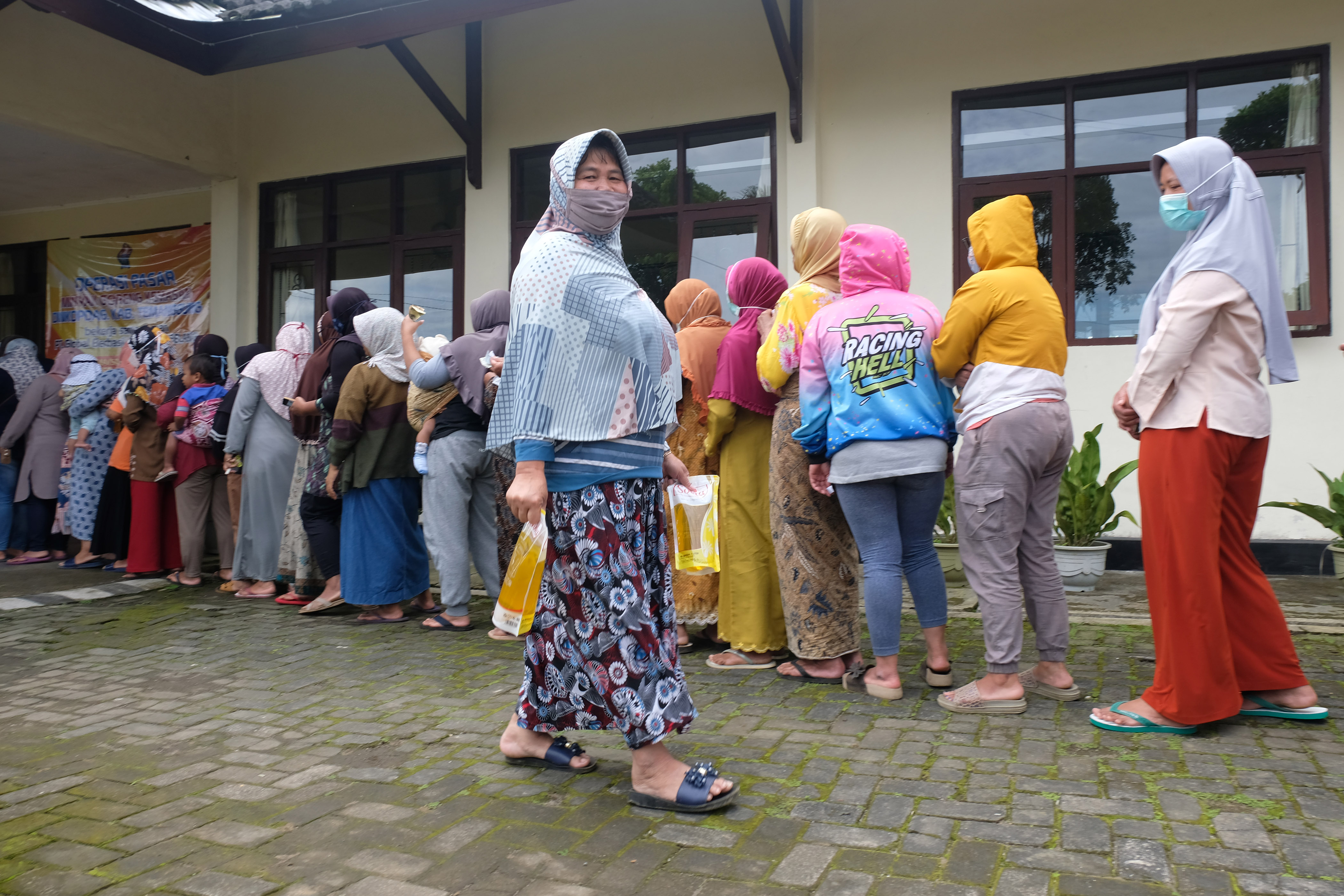 Warga antre membeli minyak goreng murah saat operasi pasar di kompleks kantor kecamatan Bansari, Temanggung, Jateng, Senin (7/3).