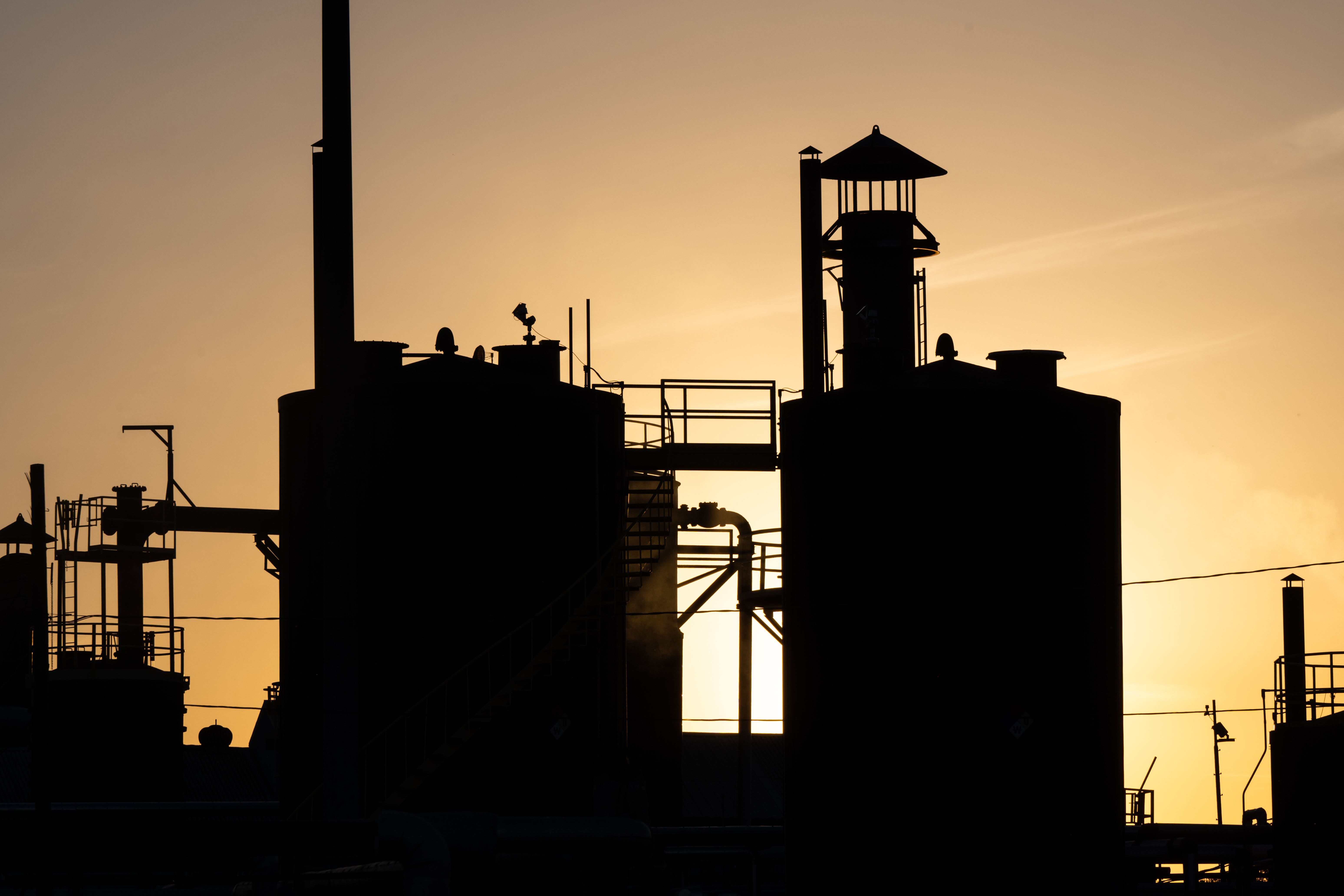 Potret matahari terbenam di teminal pengolahan minyak.