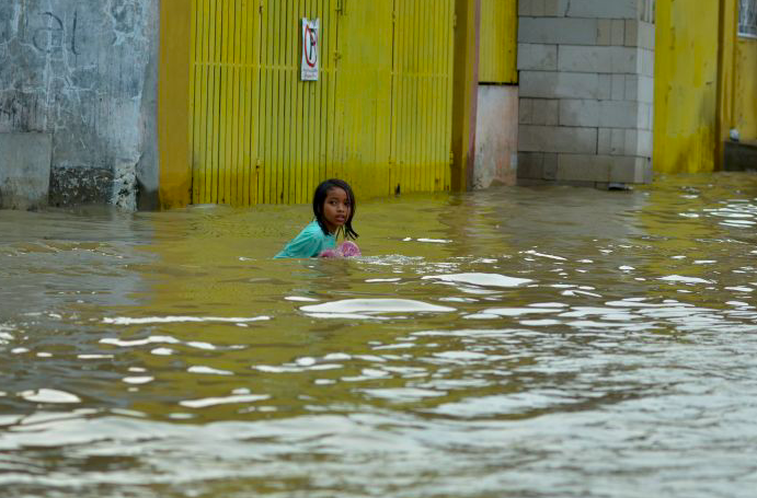 Seorang anak bermain banjir di Perumahan Villa Indah Permai, Bekasi, Jawa Barat, Minggu (16/1).