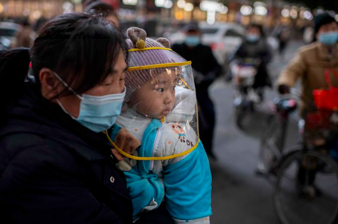 Seorang ibu menggendong bayinya di Wuhan, Tiongkok.