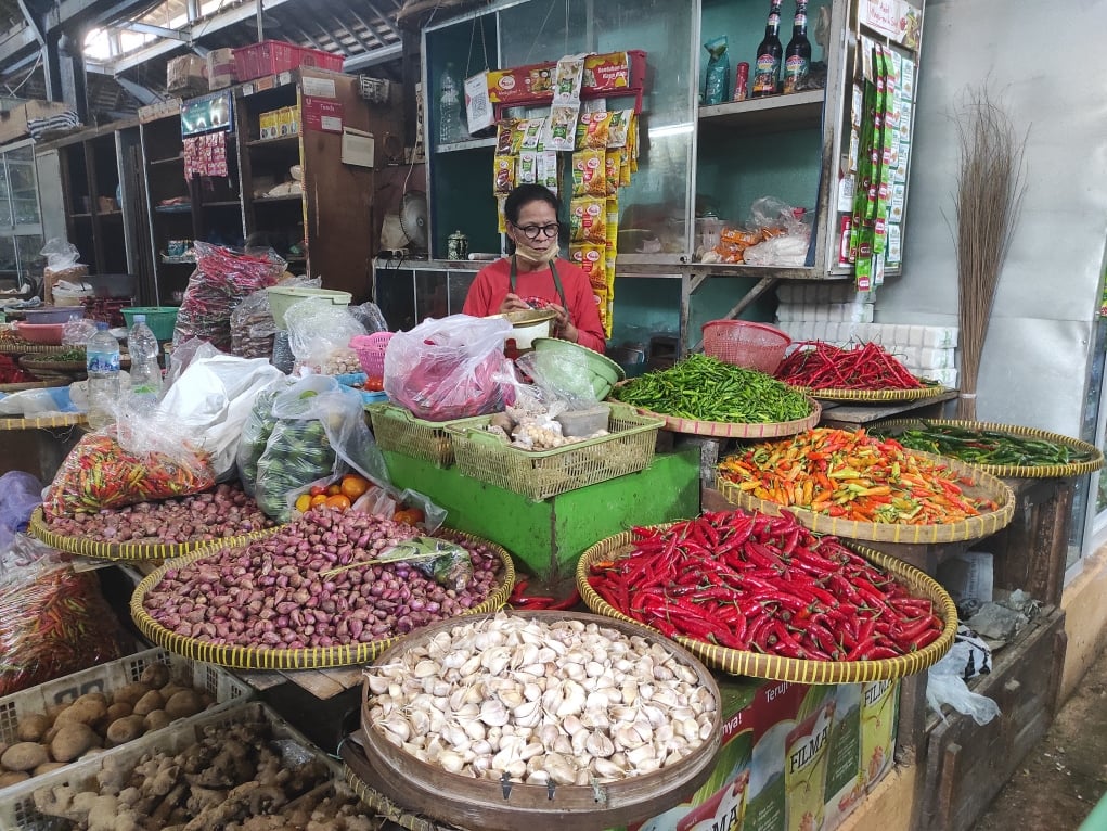 Seorang pedagang di Pasar Gede menunggu pembeli di tengah ketersediaan bahan pokok yang melimpah.