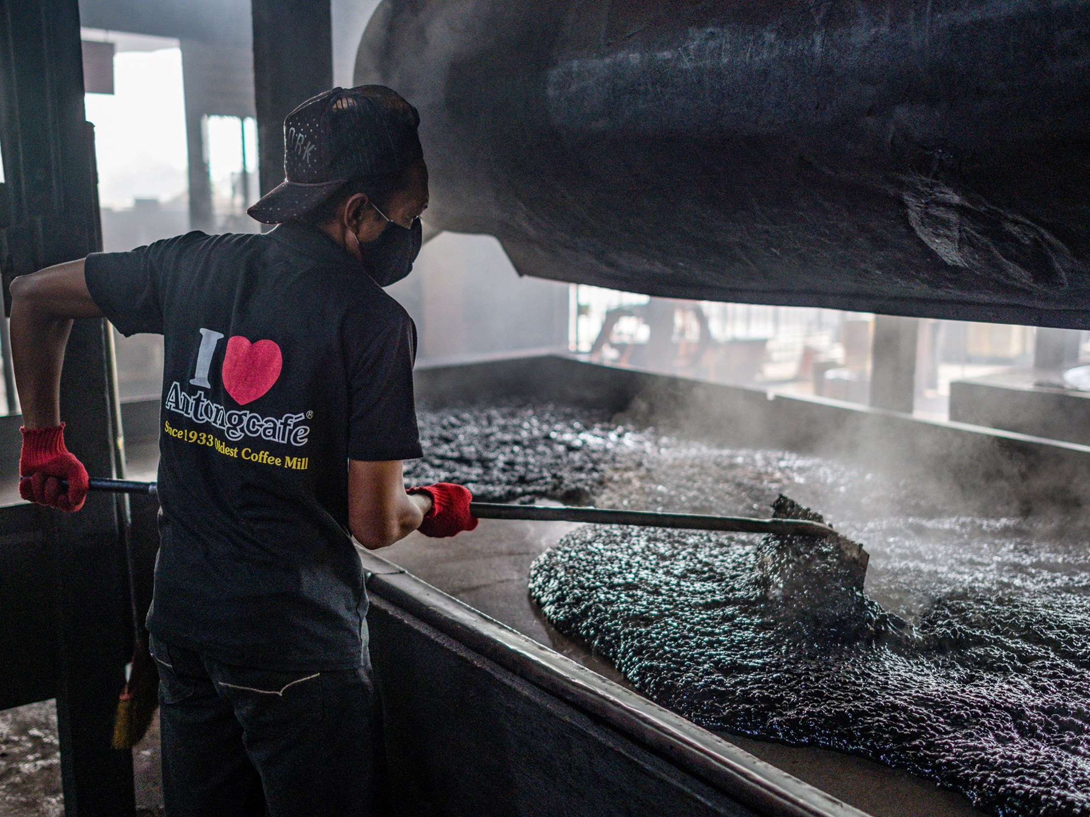 Pekerja sedang mendinginkan kopi hitam yang sudah dimaniskan sebelumnya di Pabrik Kopi Antong di Taiping di negara bagian Perak, Malaysia.
