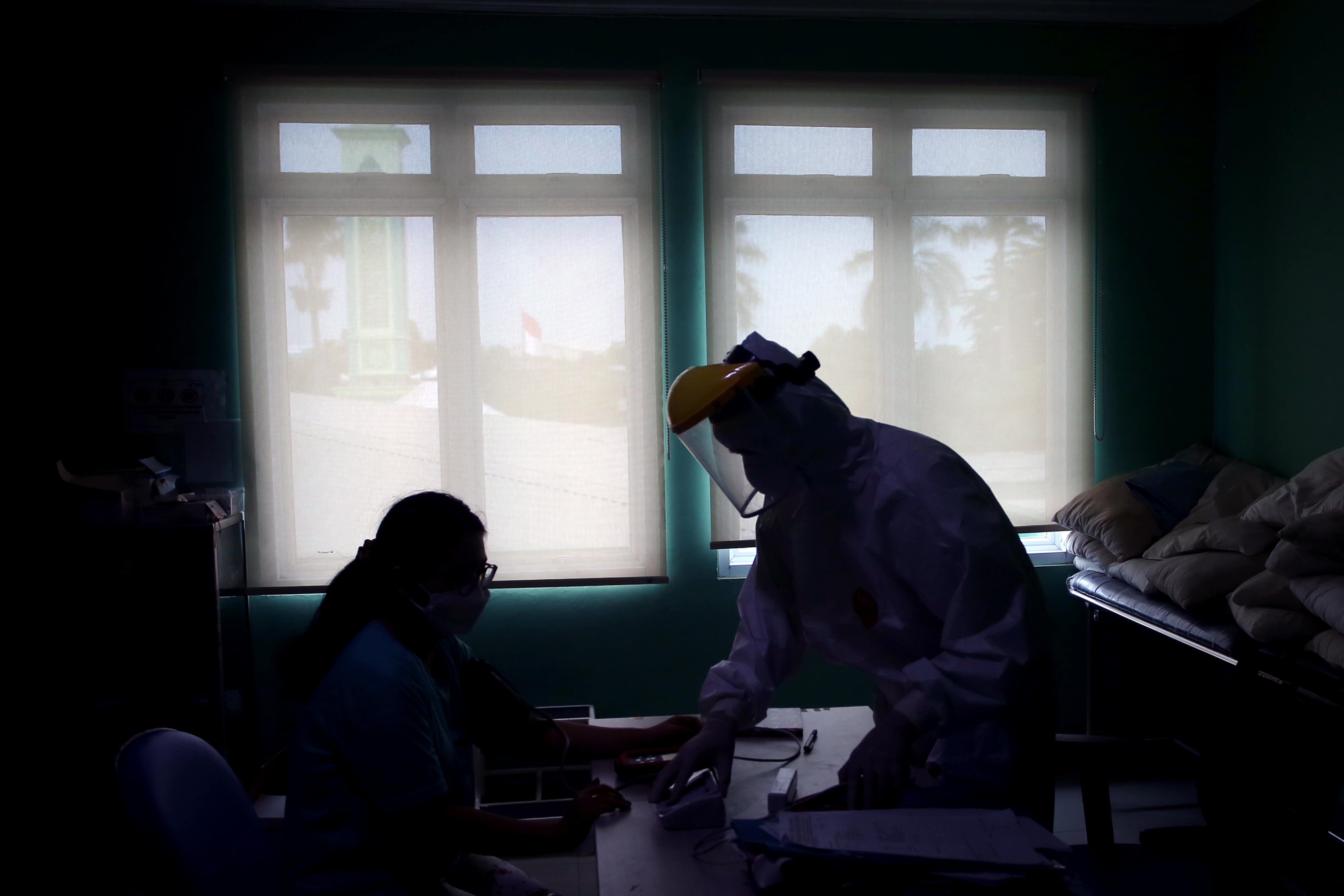 Tenaga kesehatan melakukan observasi kepada seorang pasien positif COVID-19 yang dirawat di Puskesmas Jurumudi, Tangerang, Banten.