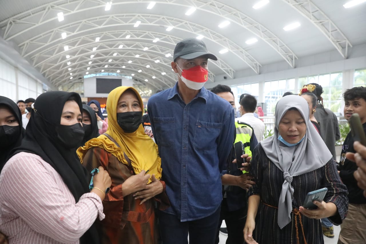 Ganjar Pranowo mengenakan topi hitam dan kemeja jeans, didampingi istrinya Siti Atiqoh Supriyanti ke official merchandise MotoGP, di bandara