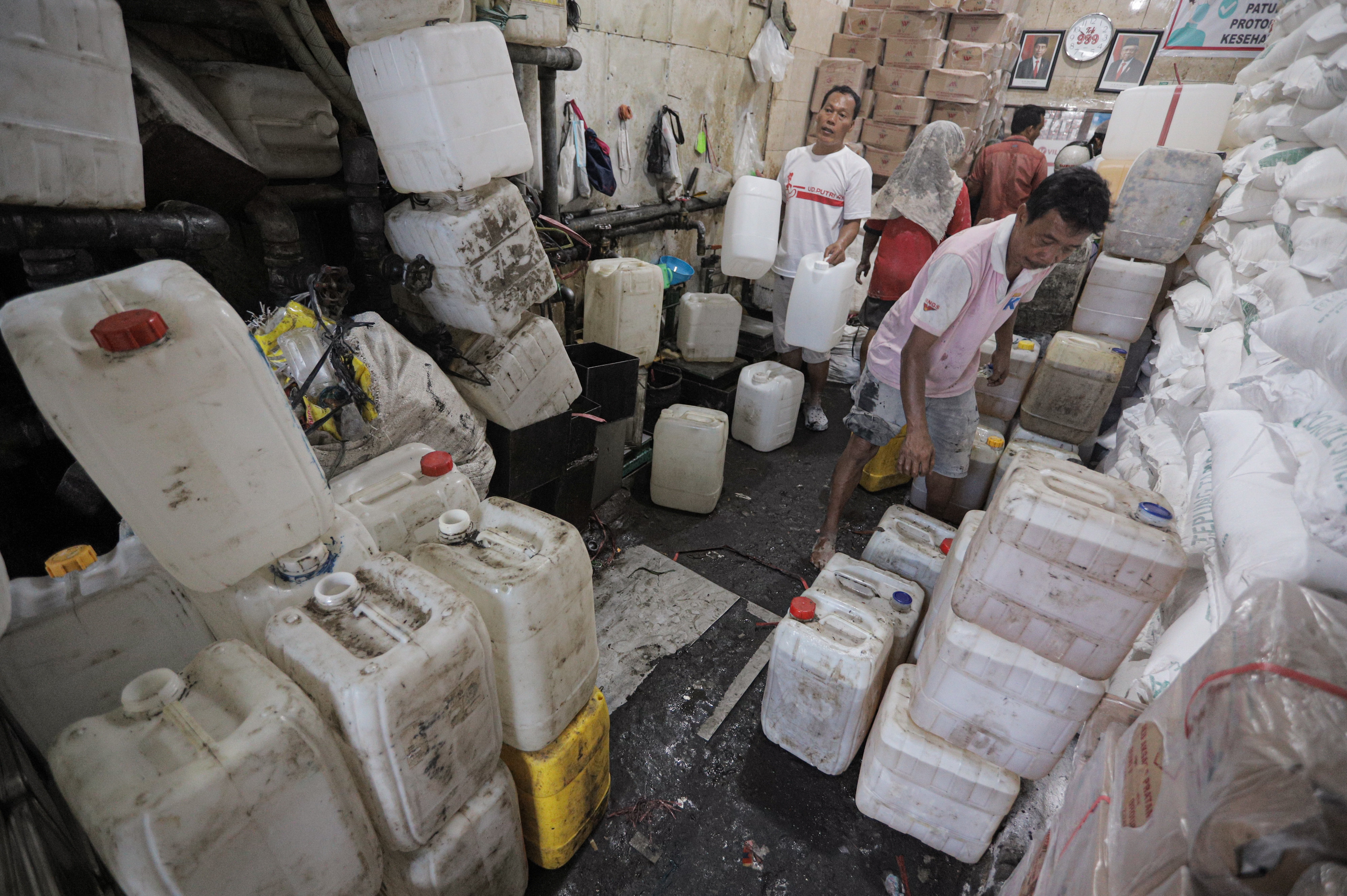 Ilustrasi pedagang di pasar menata jeriken yang berisi minyak goreng curah.