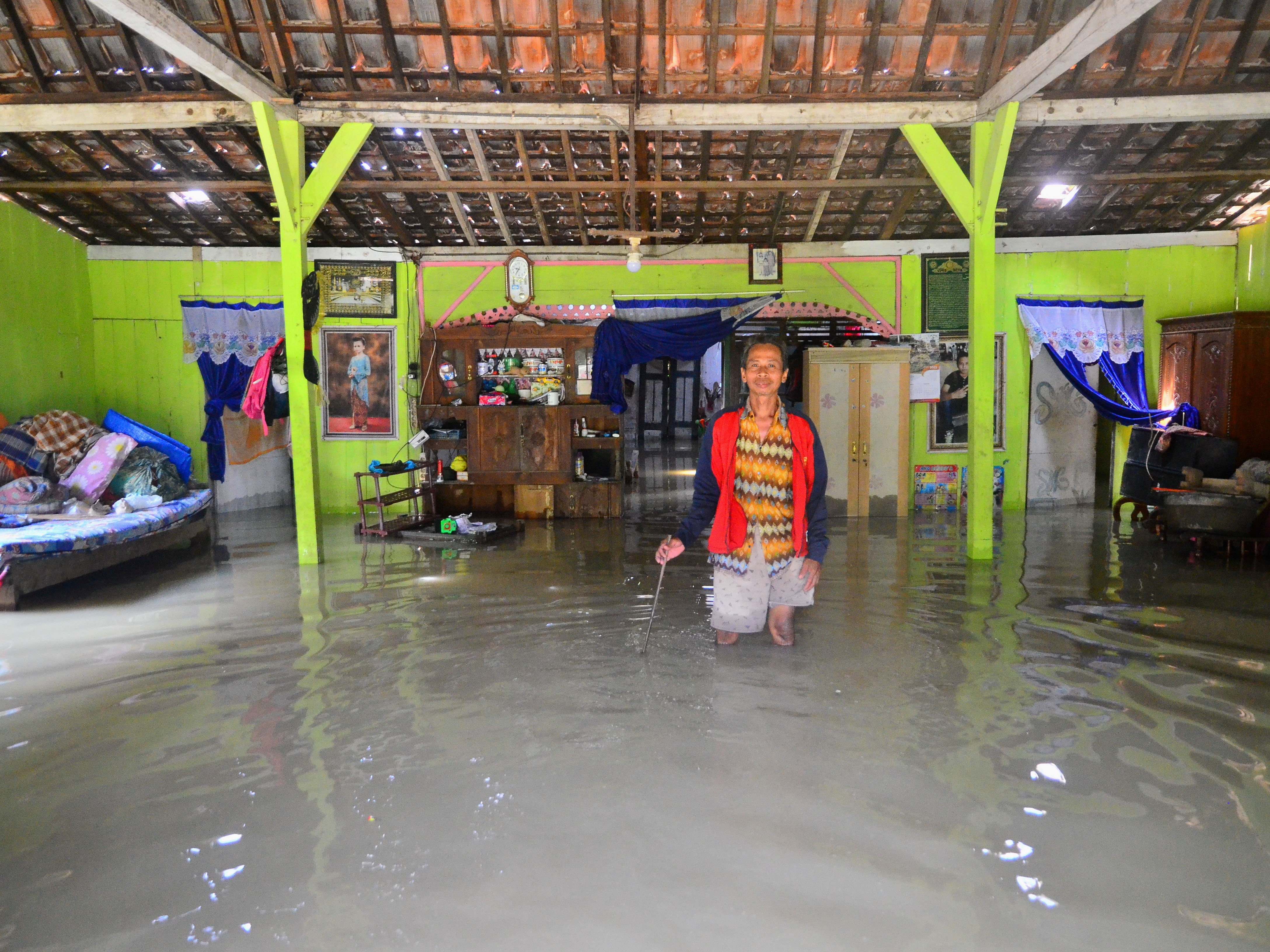 Warga berdiri di dalam rumah yang tergenang air di Desa Cingrong, Purwodadi, Grobogan, Jawa Tengah, Rabu (16/3/2022). 