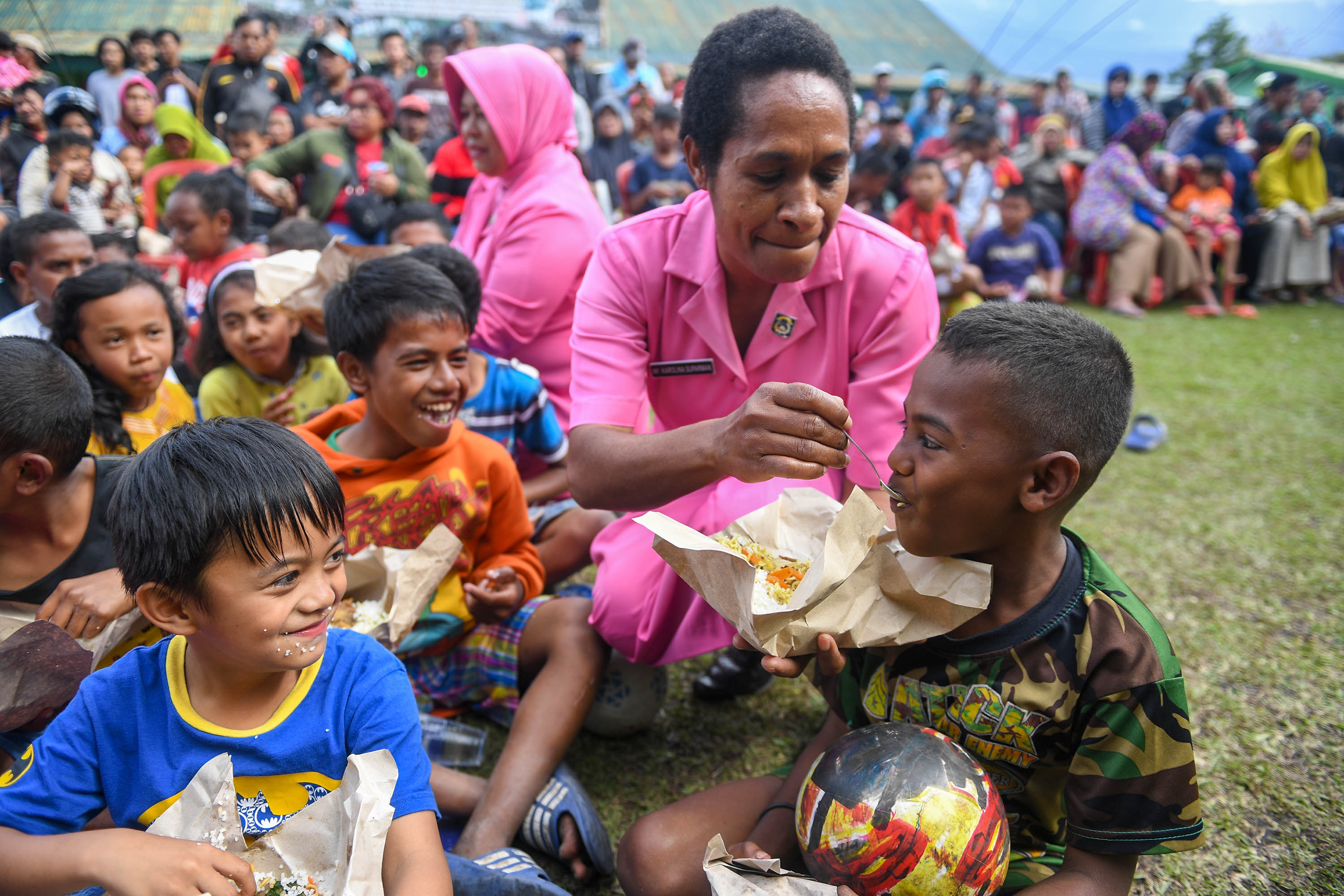 Dua orang Ibu Bhayangkari menyuapi makan pada bocah pengungsi di Posko pengungsian di Makodim 1702/Jayawijaya, Wamena, Papua.